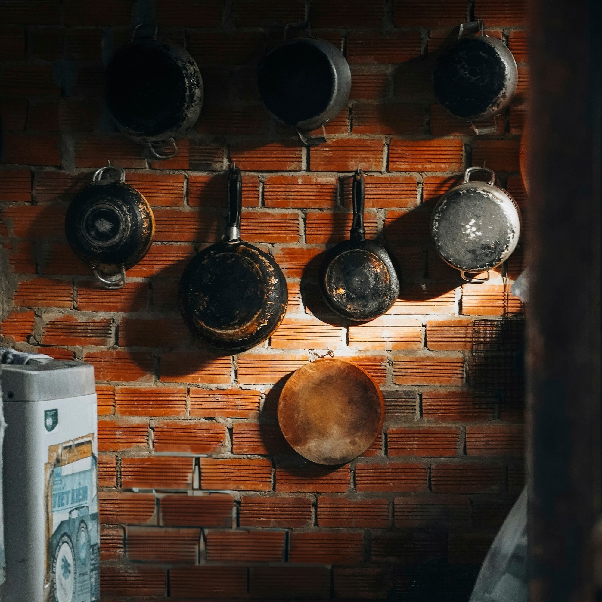 Weathered cast iron pans hanging on a rustic brick wall in a Western ranch kitchen