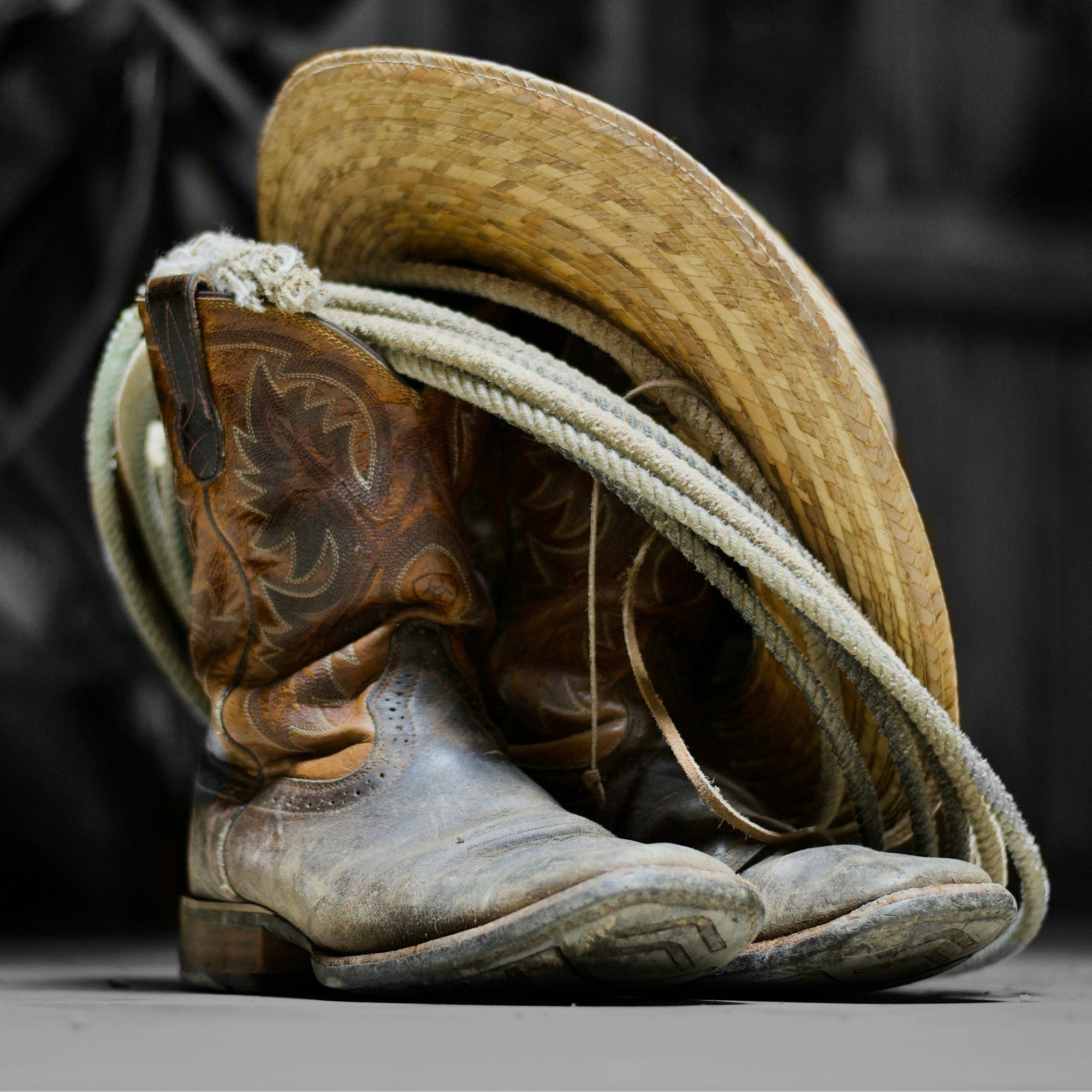 Worn leather cowboy boots resting on a rustic wooden floor
