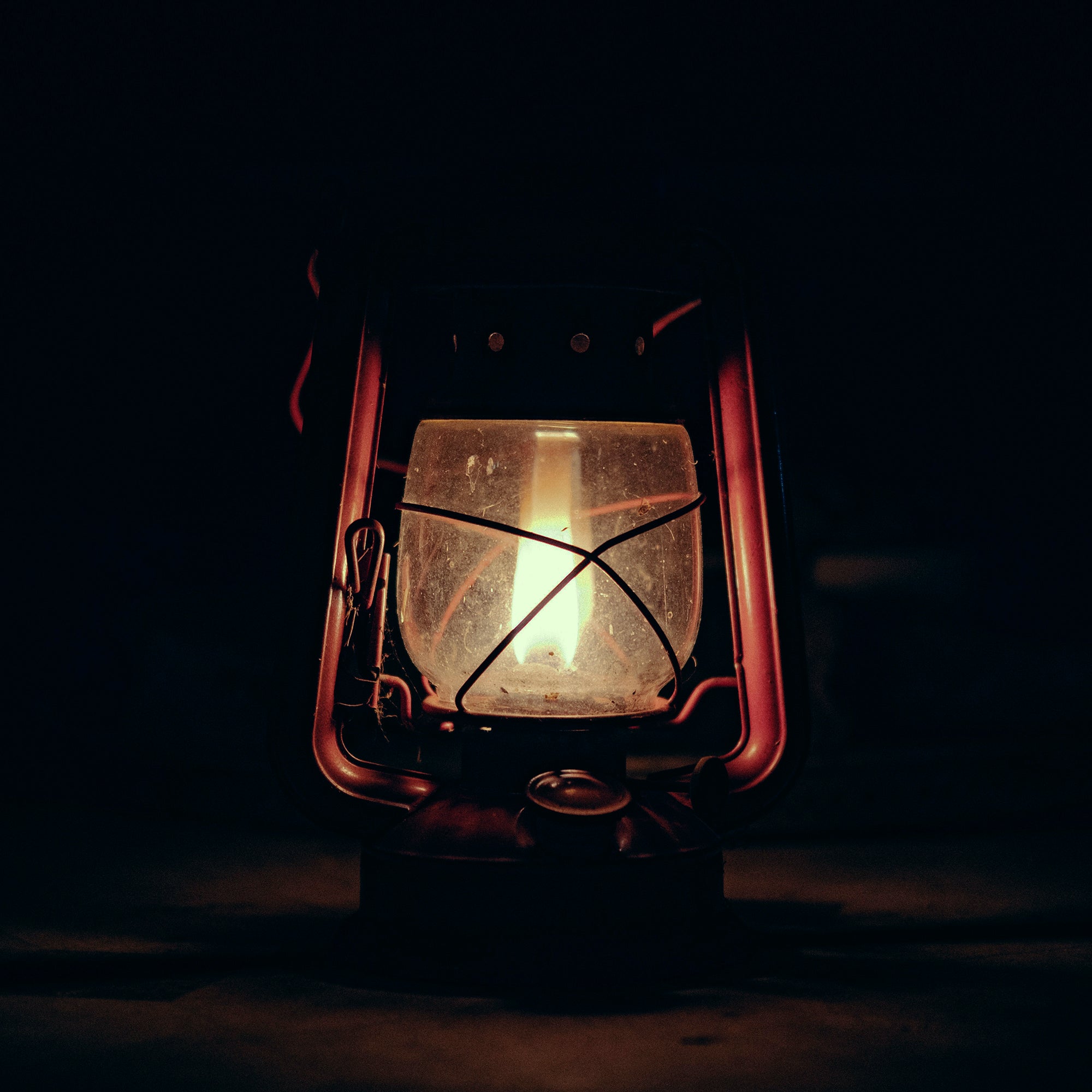 Warm porch light glowing at dusk outside a rustic Western ranch home