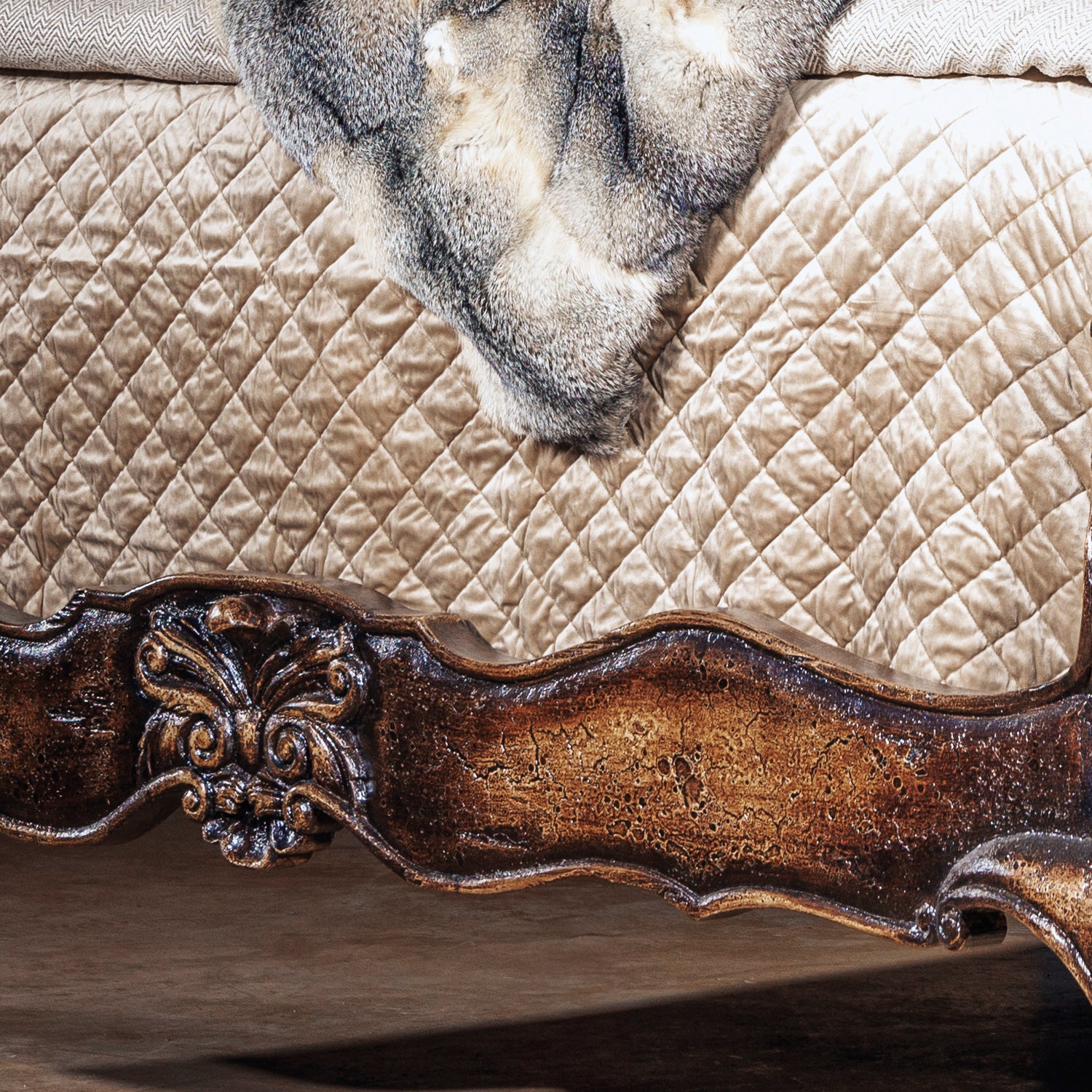 Romantic western bed with curved carved headboard and antiqued wood finish in an intimate bedroom