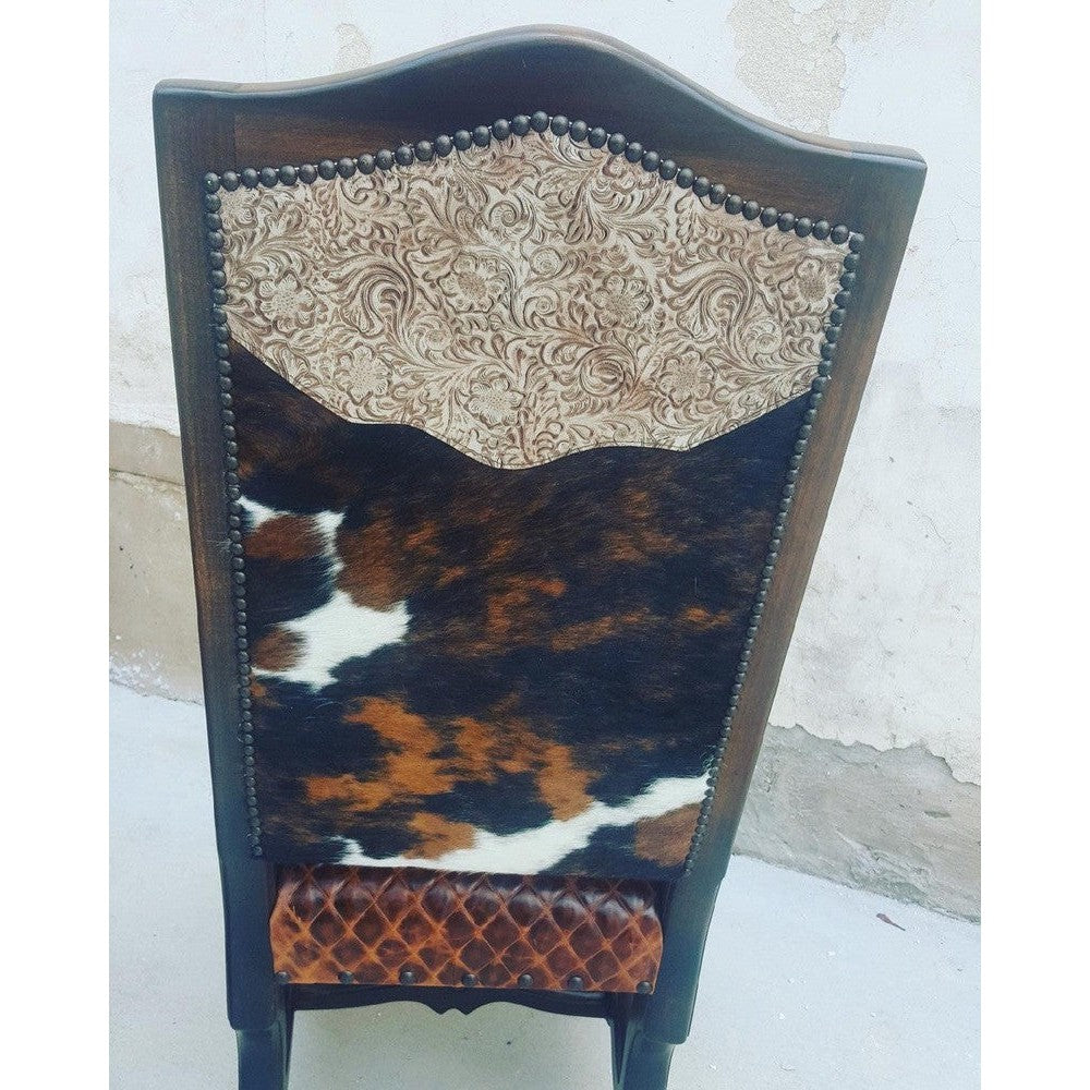 Experience luxurious comfort and style with the Tolbert Dining Chair. It is expertly crafted with top grain leather and tri-colored cowhide upholstery, providing a plush seating experience. With a diamond stitch seat and solid wood frame and trim, this chair adds both glamour and durability to any room.