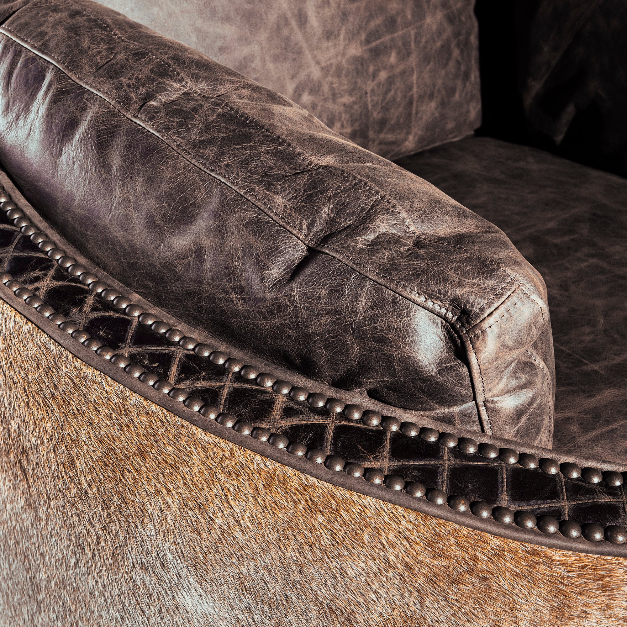 Close-up of leather arm and nailhead trim on Bitterroot Hide Cuddler Recliner, premium Western recliner detail