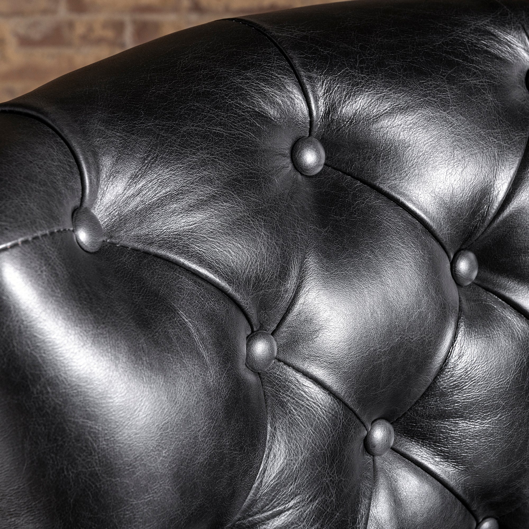 Close-up of button-tufted black leather backrest on Western bar stool—tailored leather upholstery detail for ranch home bar