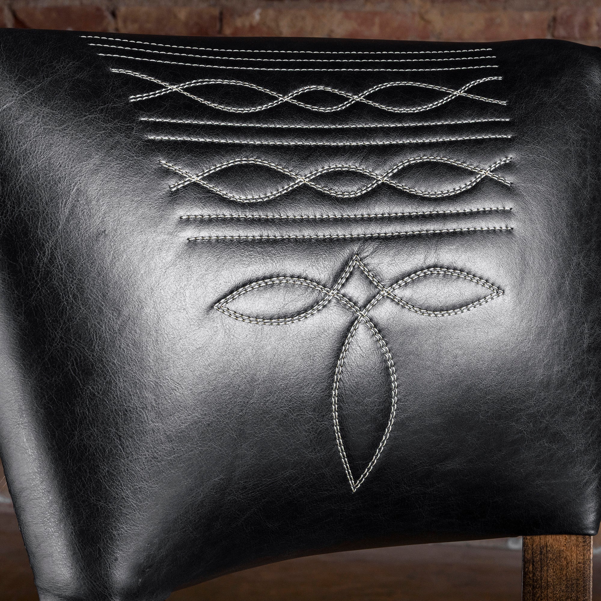 Close-up of bootstitch embroidery on black leather backrest of Western bar stool