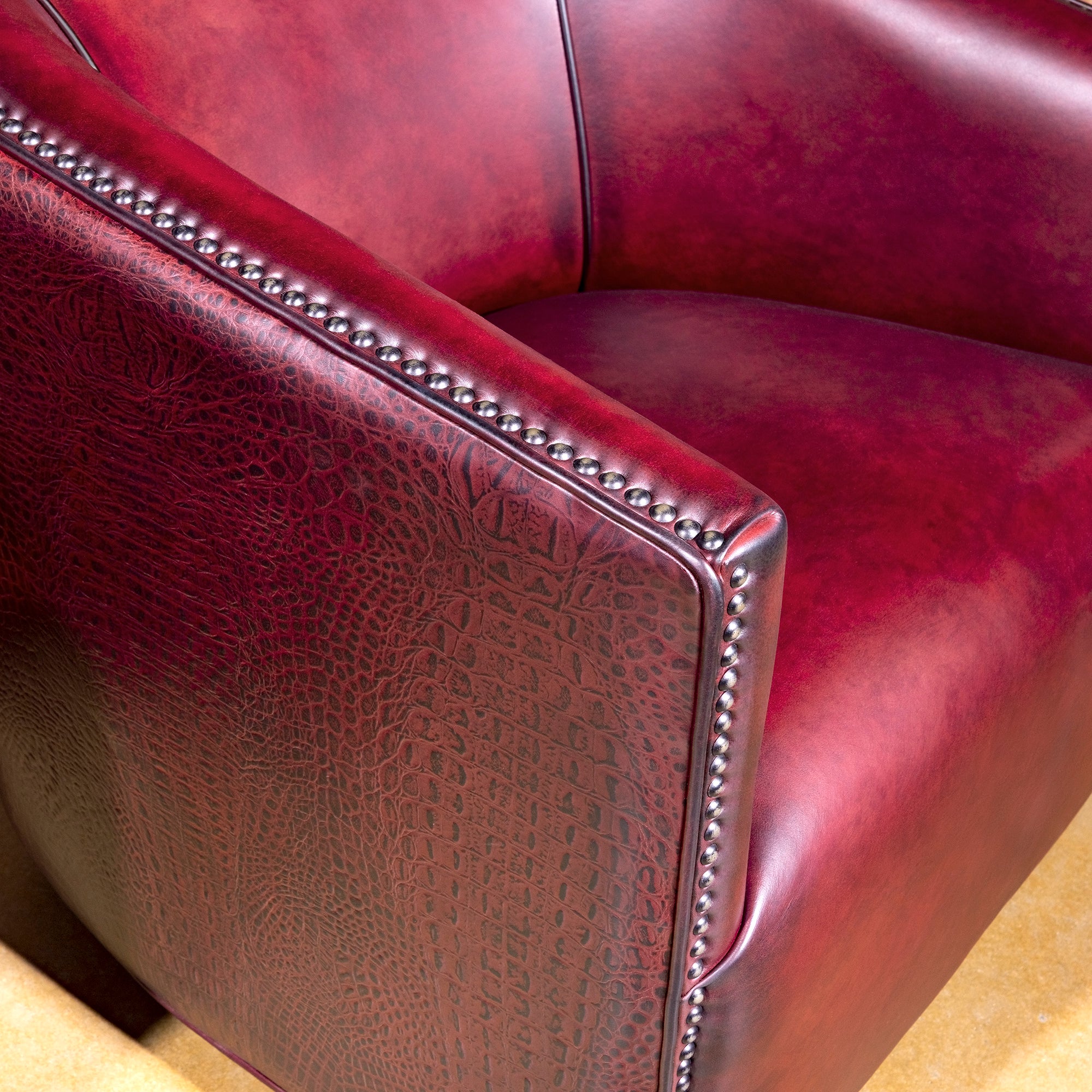 Bordeaux Croc Chair western swivel chair closeup with red leather seat, croc texture, and bronze nailhead trim