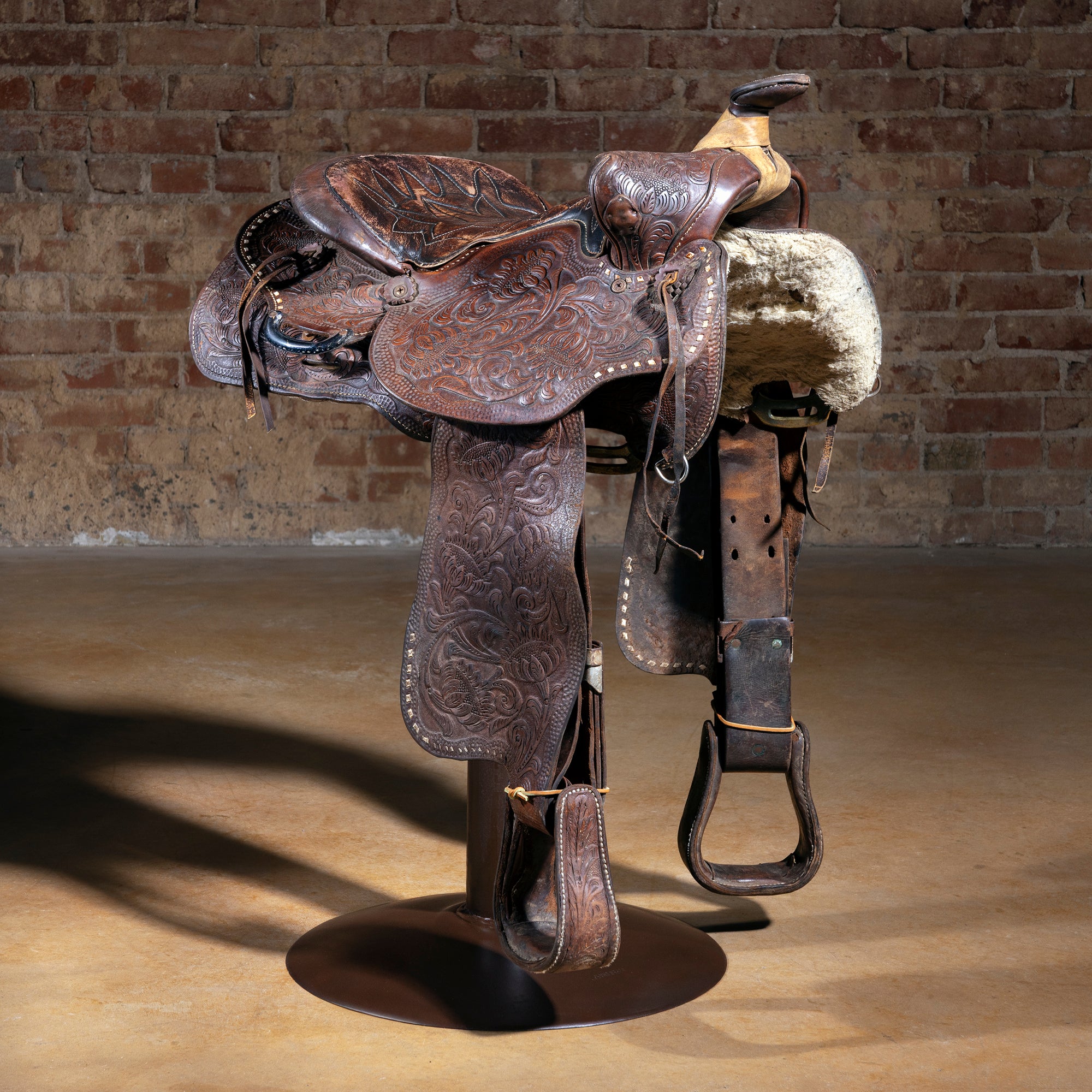 Bridle Spur Western saddle bar stool with detailed tooled leather saddle on iron pedestal