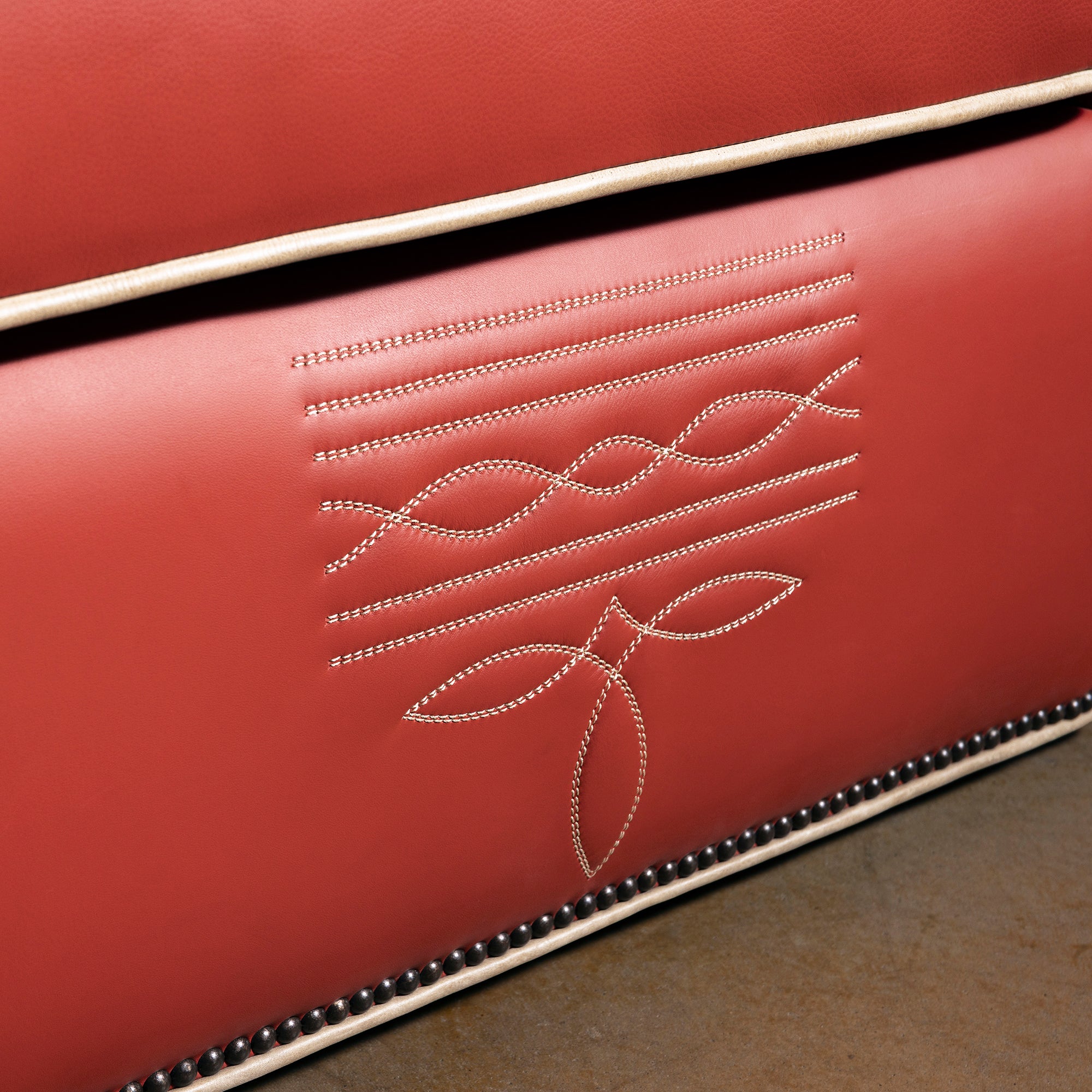 Closeup of bootstitch-inspired embroidery on coral-red leather chair front panel