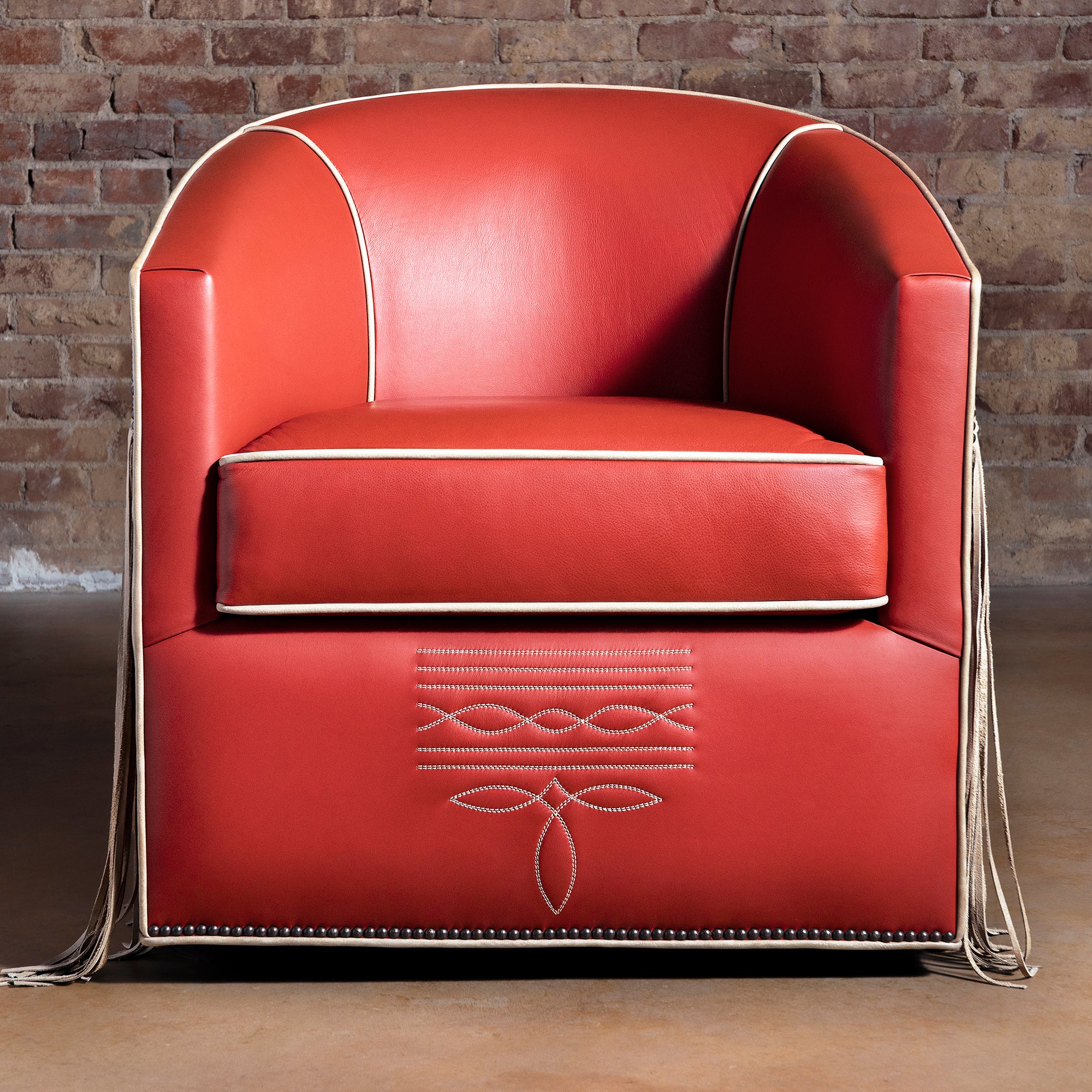 Front view of coral-red leather swivel chair with bootstitch detail and tailored piping