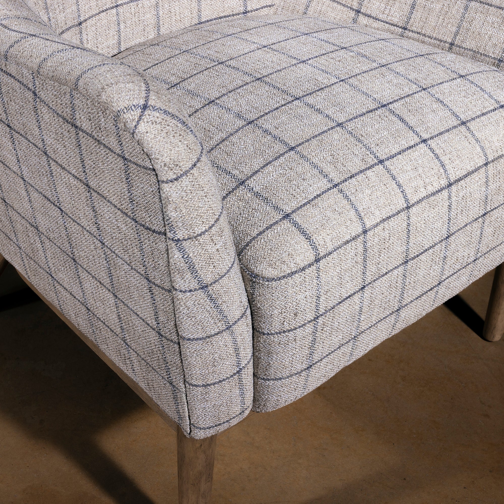 Close-up of upholstered seat and arm on windowpane fabric chair, lodge-style ranch chair cushion and weave detail