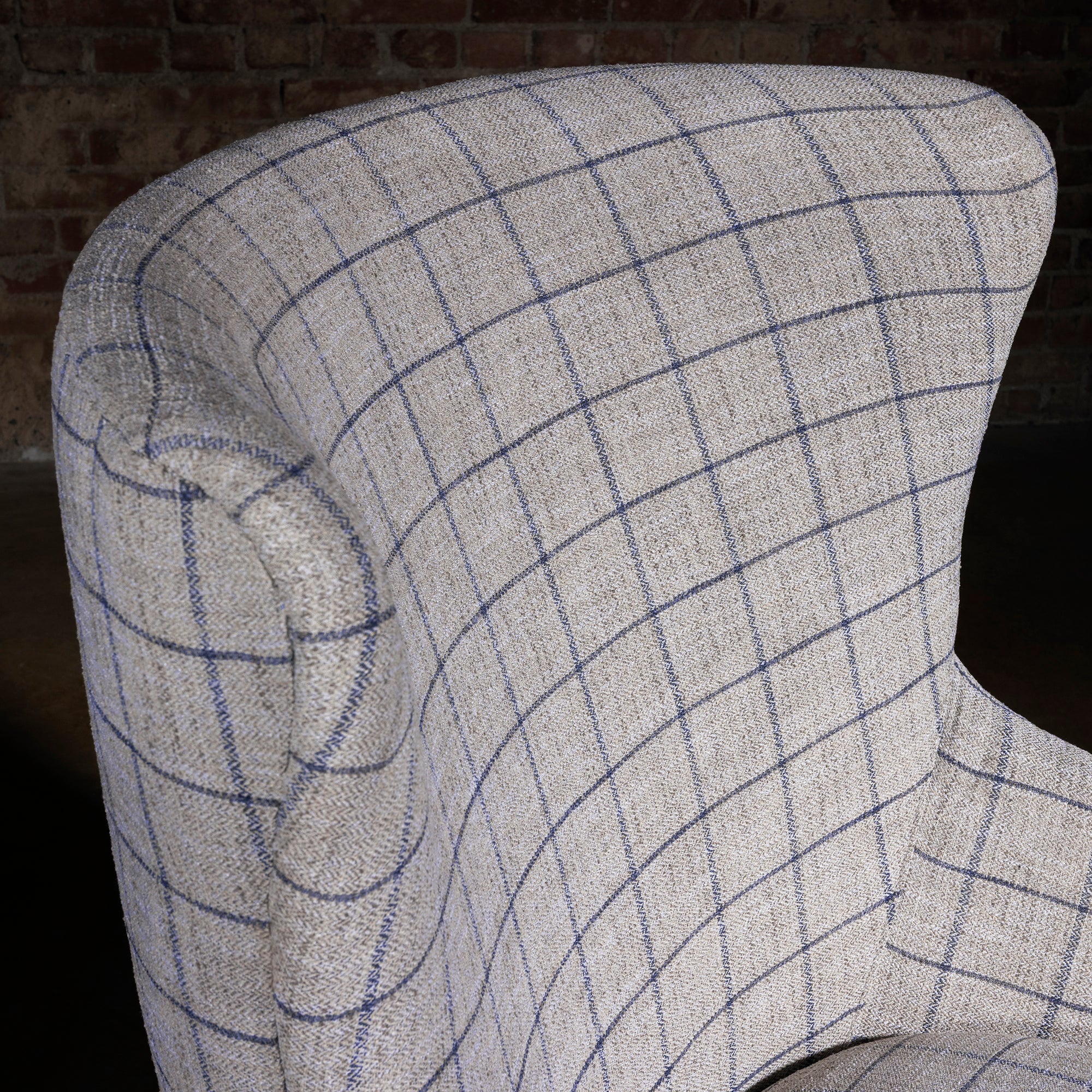 Close-up of windowpane plaid fabric on curved high back, upscale western accent chair upholstery texture