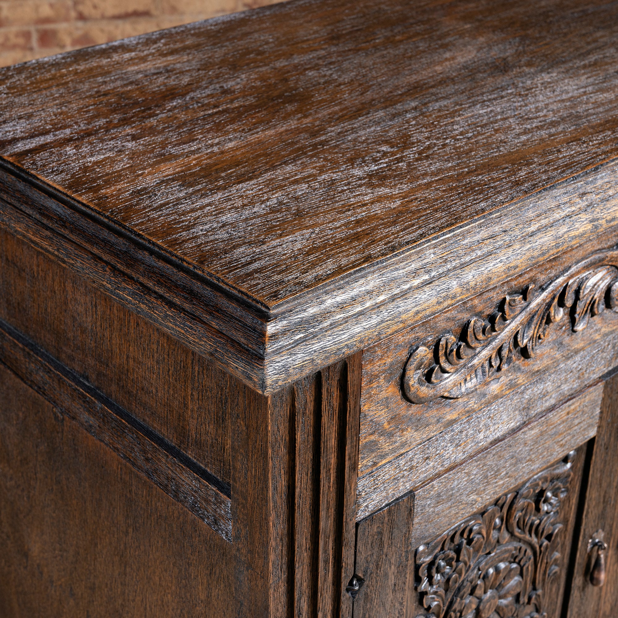 Closeup of distressed dark-wood top corner on carved Western nightstand with heirloom rustic texture