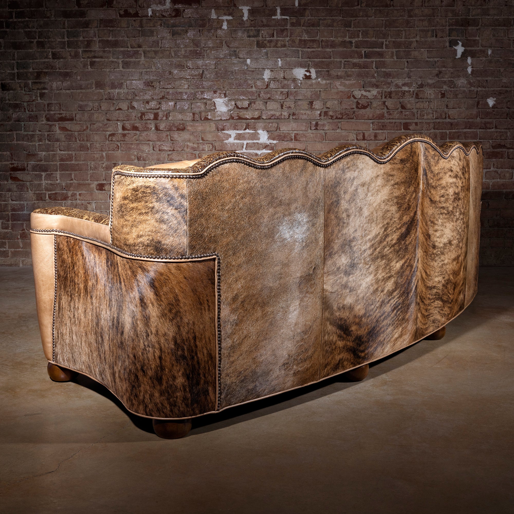 Angled back view of Brazilian cowhide panels with tooled leather trim on sofa