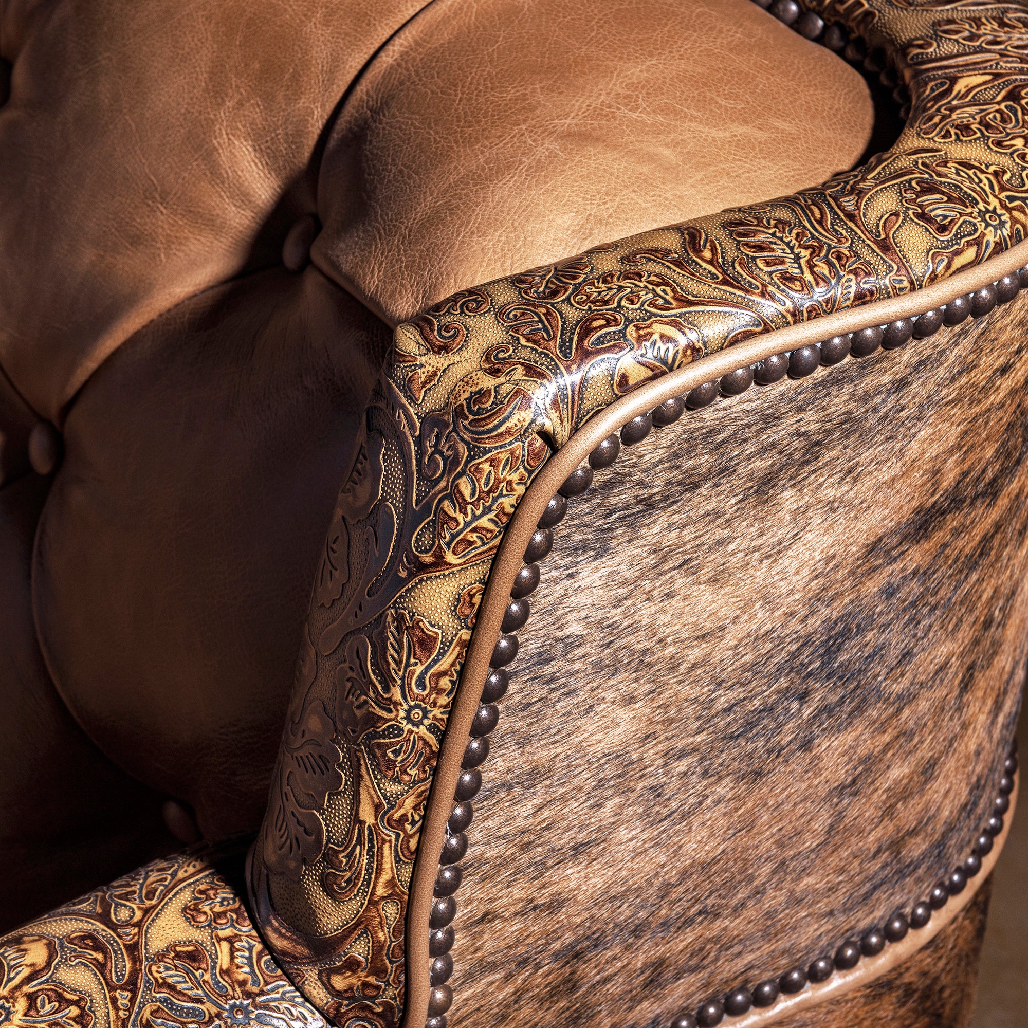 Tooled leather top rail detail on scalloped-back Western tufted leather sofa