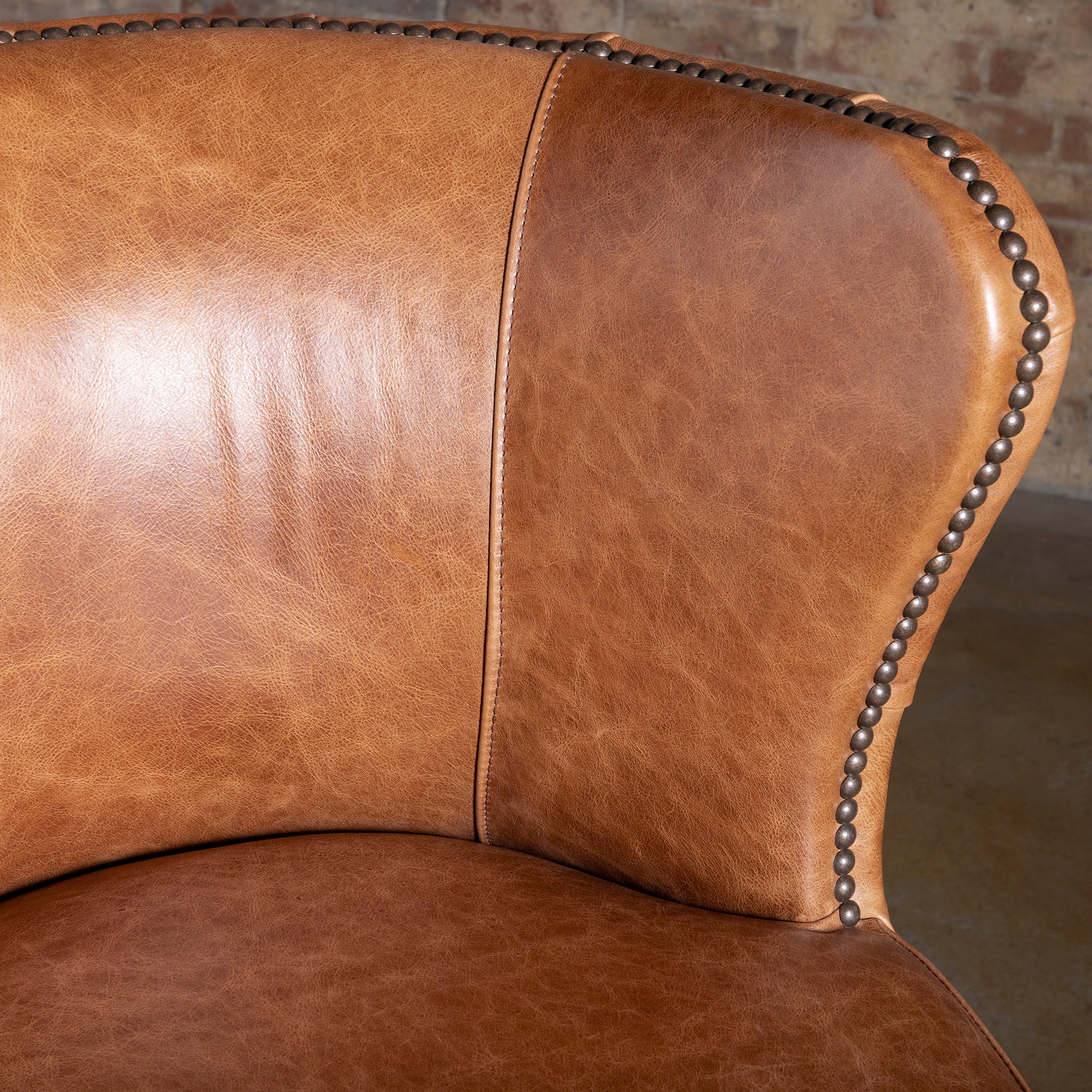 Closeup of saddle tan leather seat on Catalina bar stool with nailhead trim and smooth edge finish