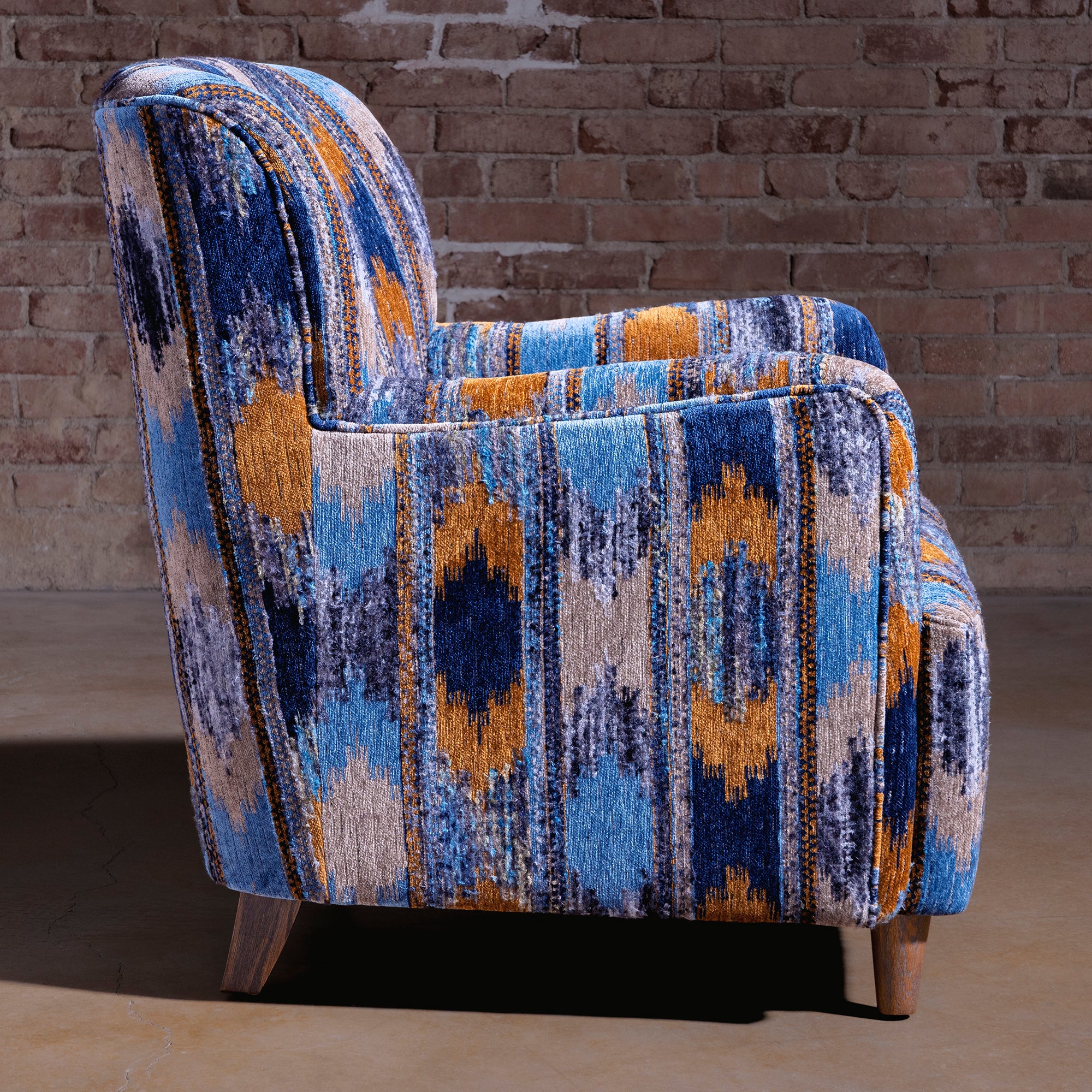 Side profile of compact upholstered accent chair in cerulean Southwestern pattern