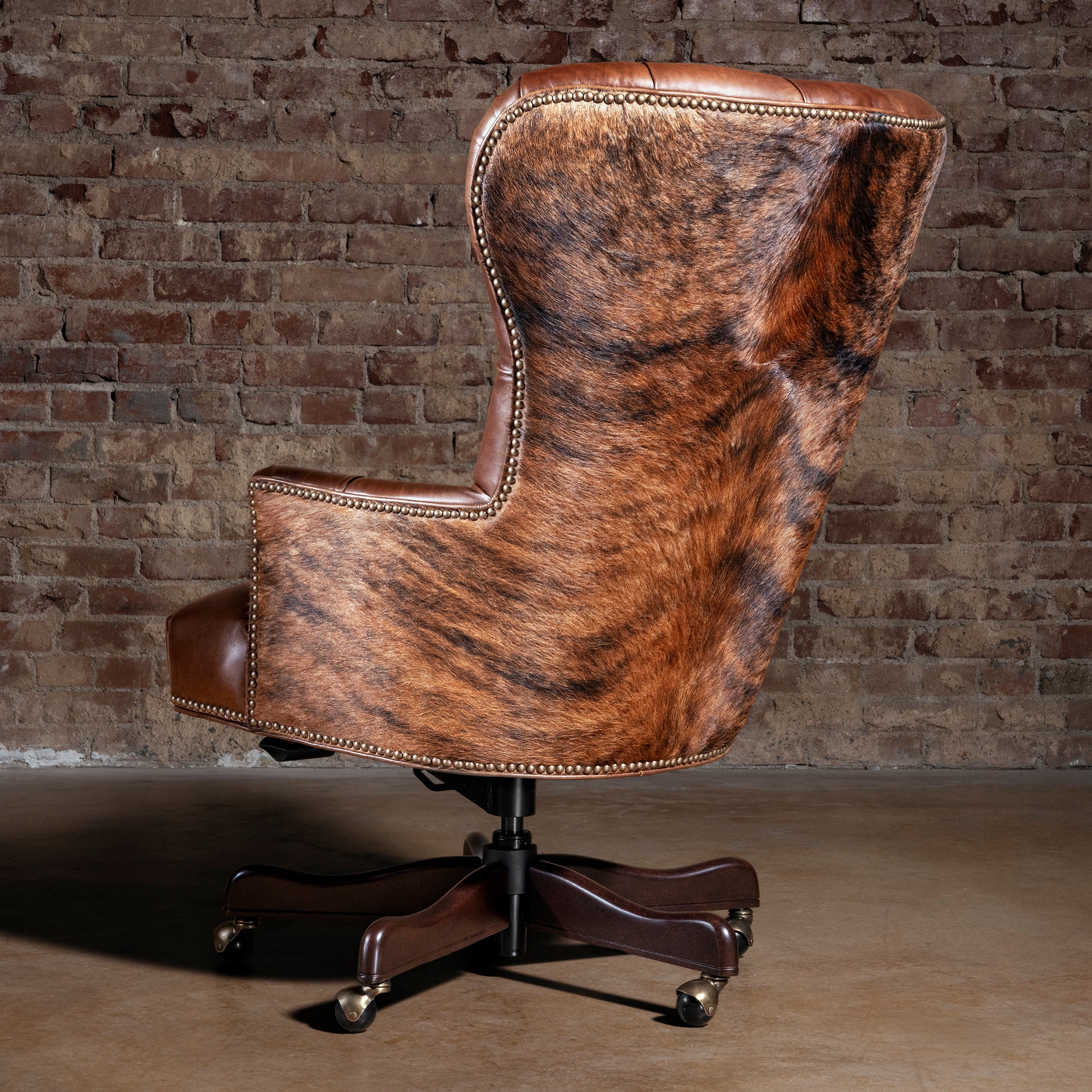 Back view of Western cowhide office chair with solid wood frame, nailhead trim, and caster base