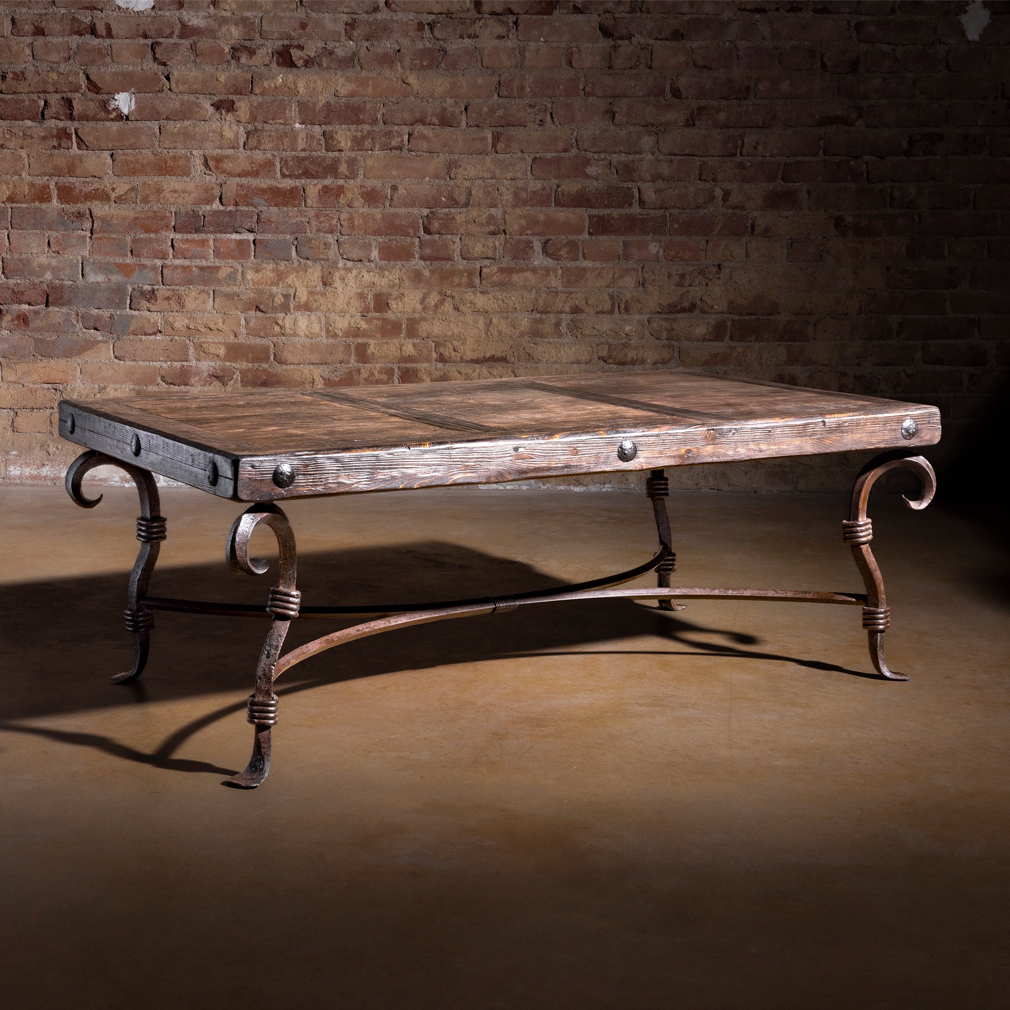 Western reclaimed wood coffee table with hand-forged iron scroll legs and rivet accents