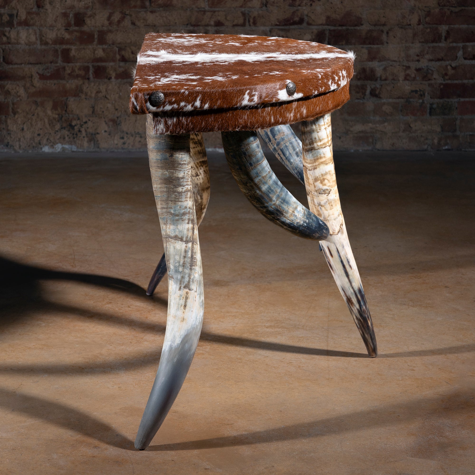 Profile view of demi-lune cowhide accent table showing horn legs and arched stance