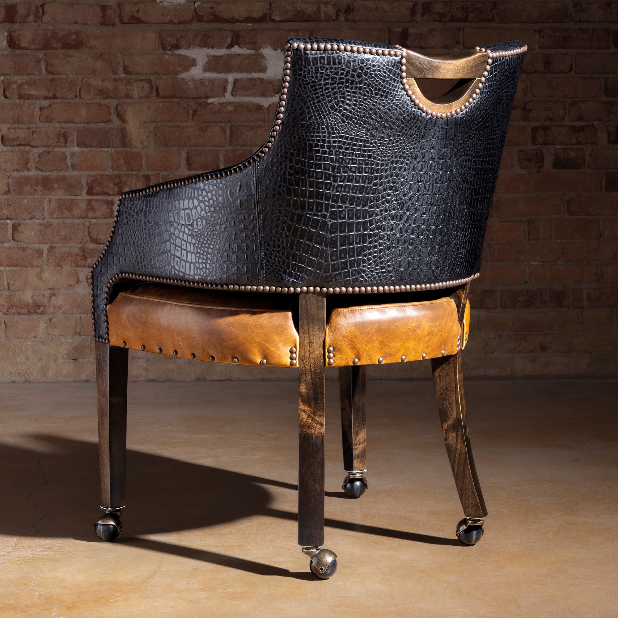 Back view of Western poker chair featuring black croc-embossed leather shell, nailhead trim, and rolling casters