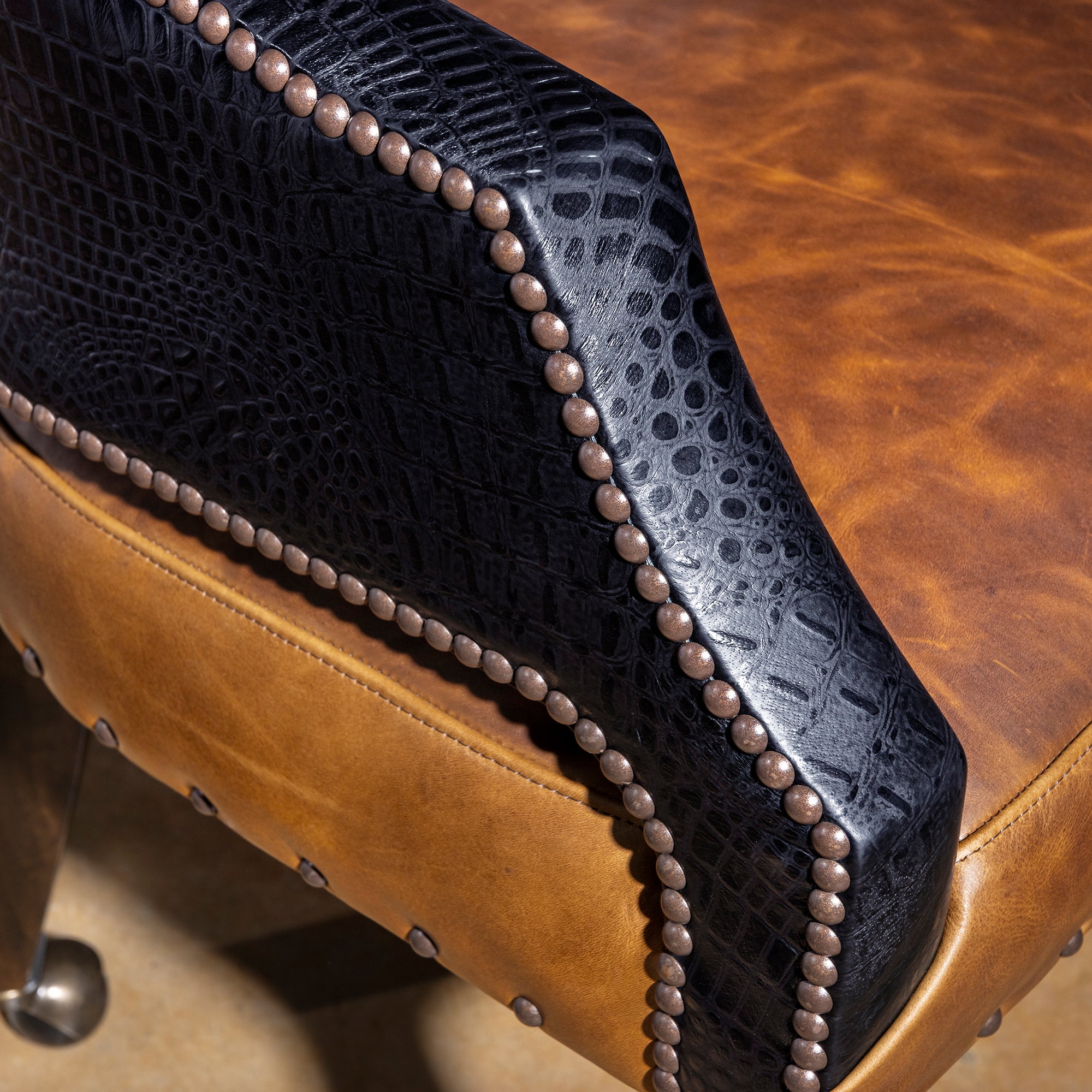 Arm detail of Western poker chair with black croc leather, bronze nailheads, and saddle top-grain leather seat