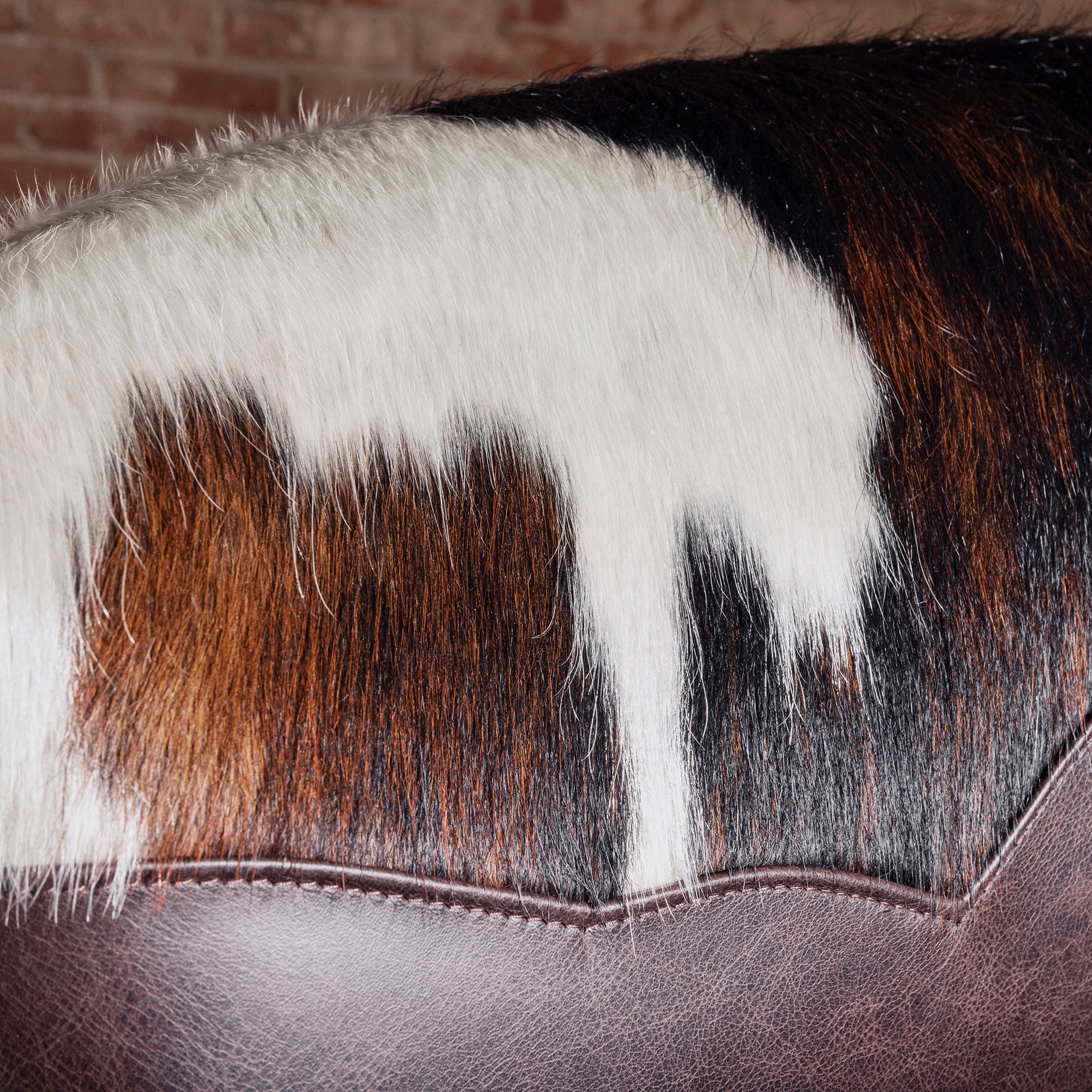 Detail of tricolor cowhide yoke and leather edge finishing on Cochise Brazilian cowhide bar stool