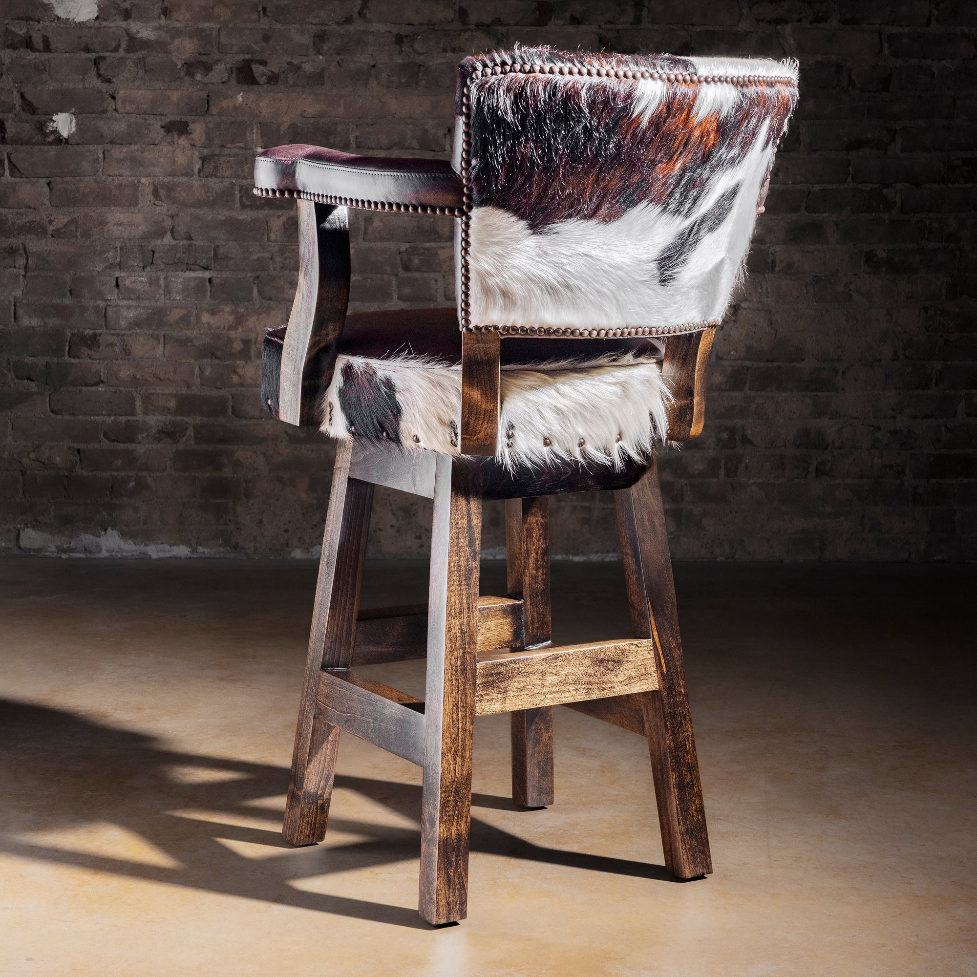 Back view of Cochise tricolor cowhide bar stool showing Brazilian cowhide panel, nailhead border, and Alder wood frame