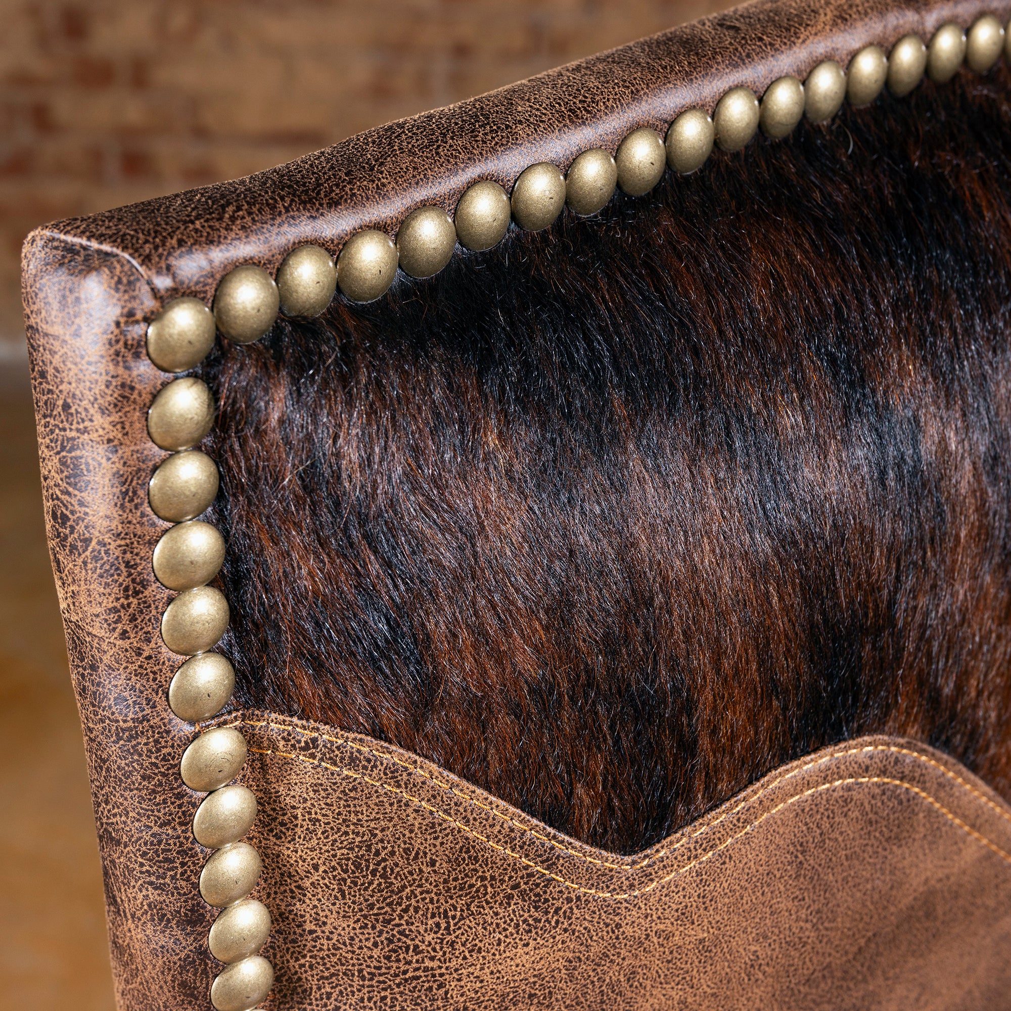 Closeup of cowhide yoke detail and nailhead trim on Western dining chair, leather-and-hide dining room chair texture