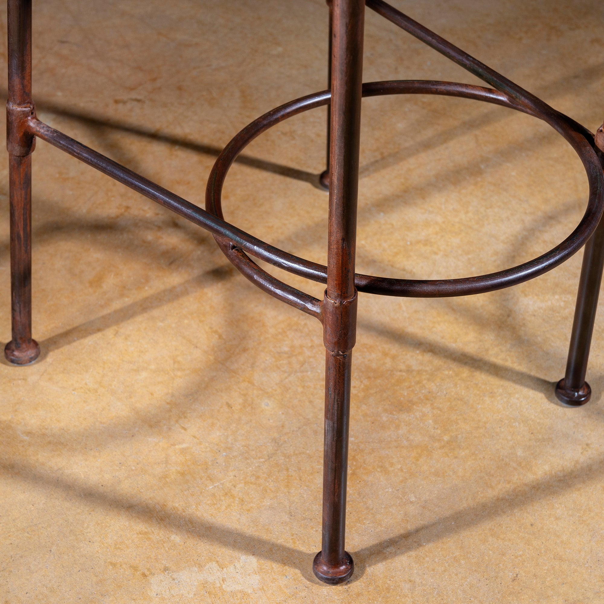 Close-up of forged iron legs and circular footrest ring on Western bar stool