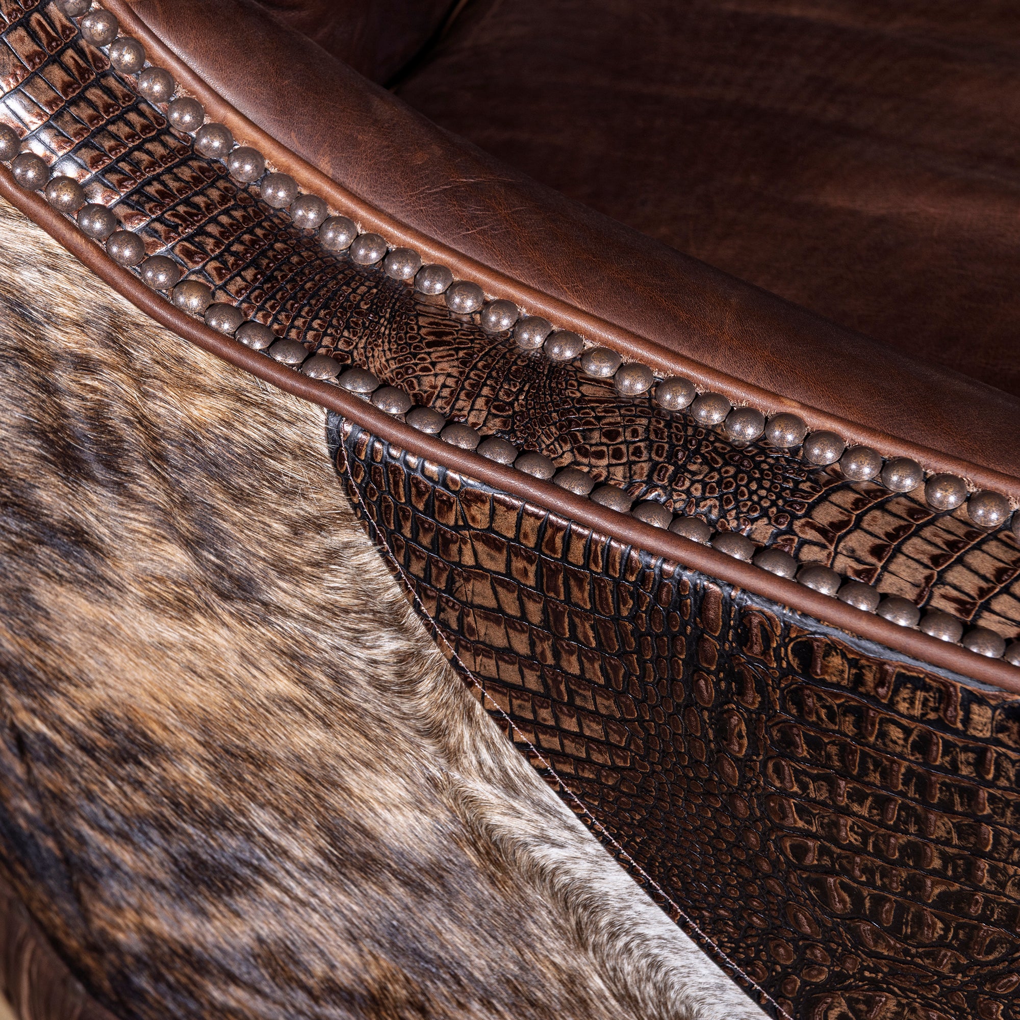 Close-up of croc-embossed leather trim, cowhide, and nailhead detail on swivel chair