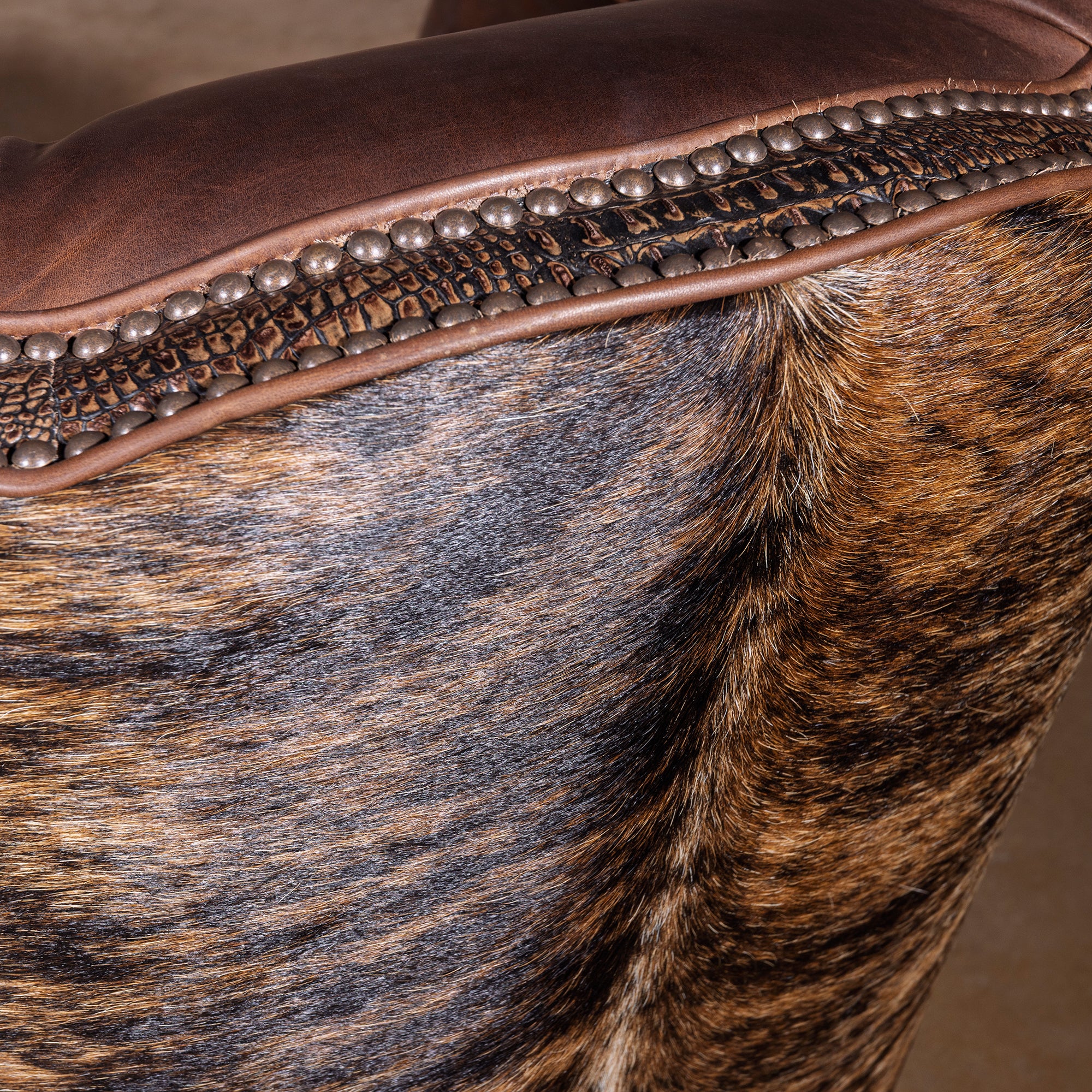 Close-up of croc-embossed leather trim and nailhead detail on swivel chair