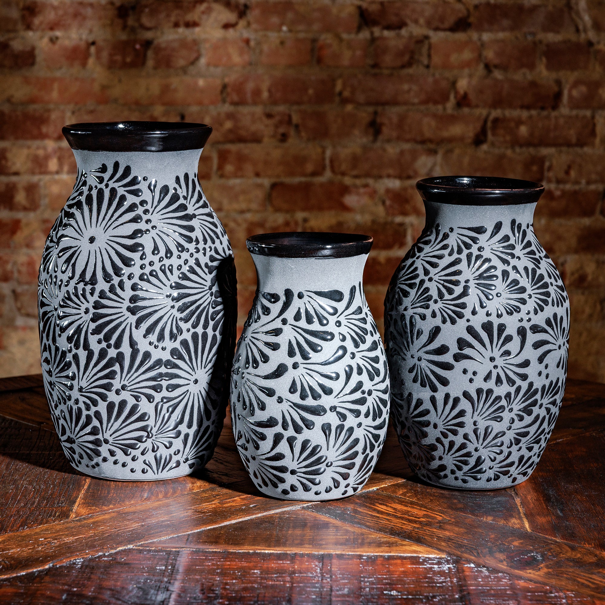 Trio of gray ceramic vases with raised black floral design