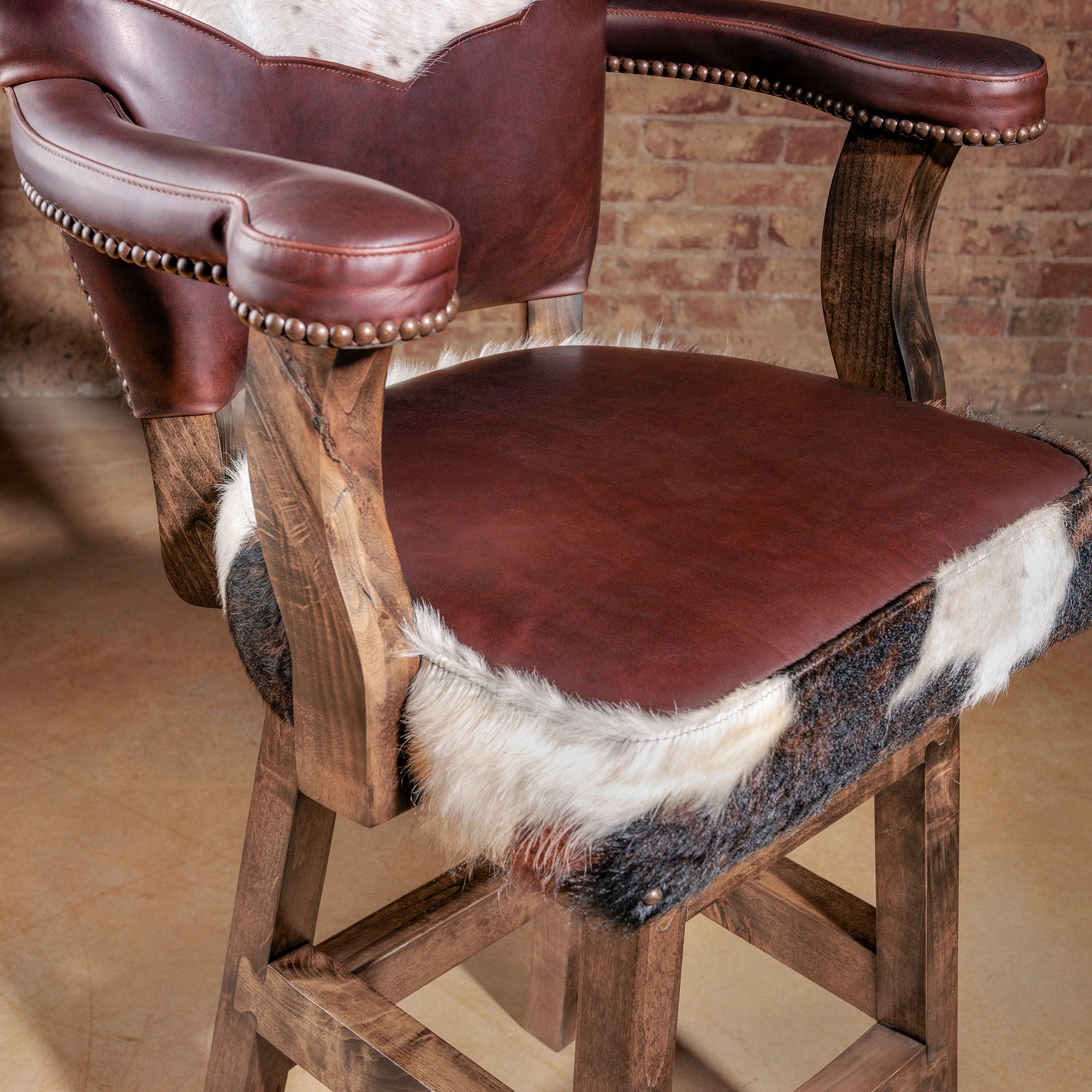 Seat detail of the High Plains Luxe Swivel Stool—brown leather seat with cowhide edge wrap, designed for comfortable everyday use at bar height seating.