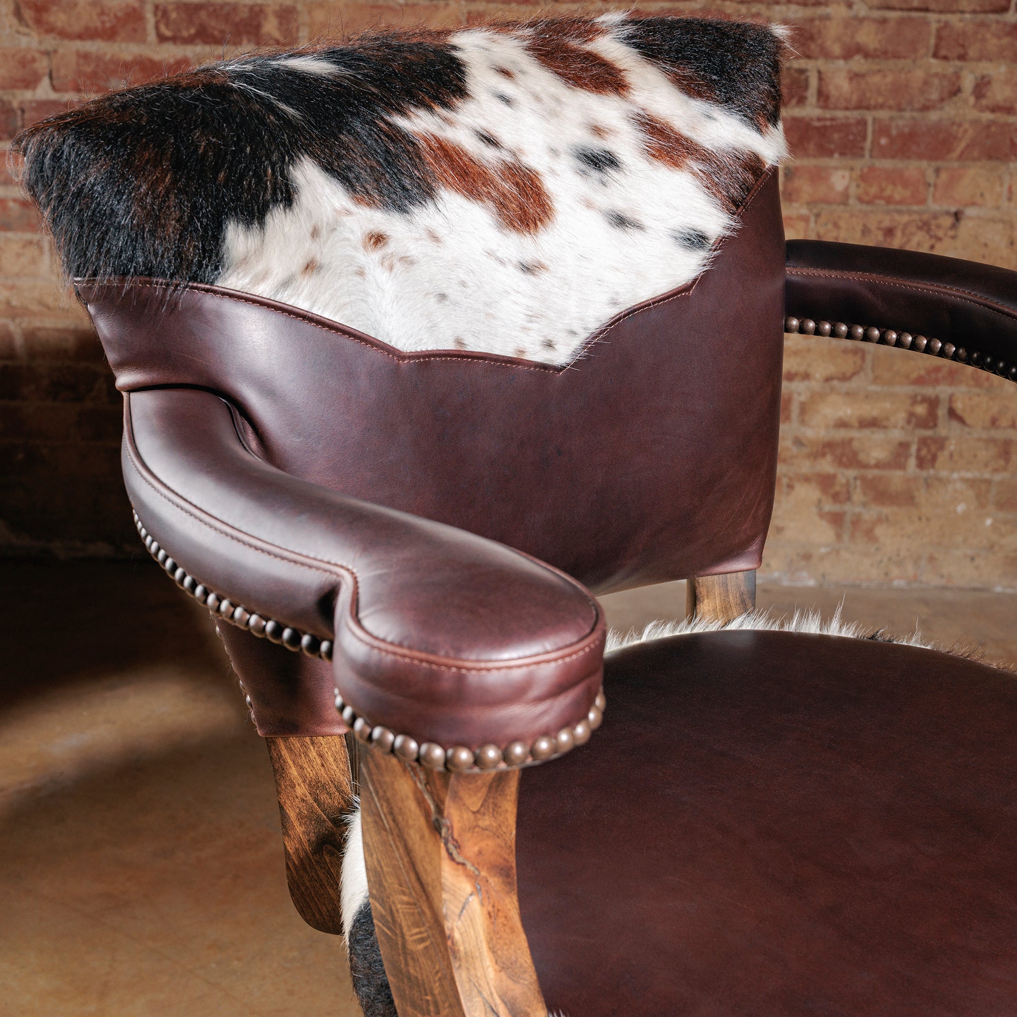 Detail of the High Plains Luxe Swivel Stool backrest—tricolor cowhide framed in brown leather, built to stand out in a Western bar or kitchen island.