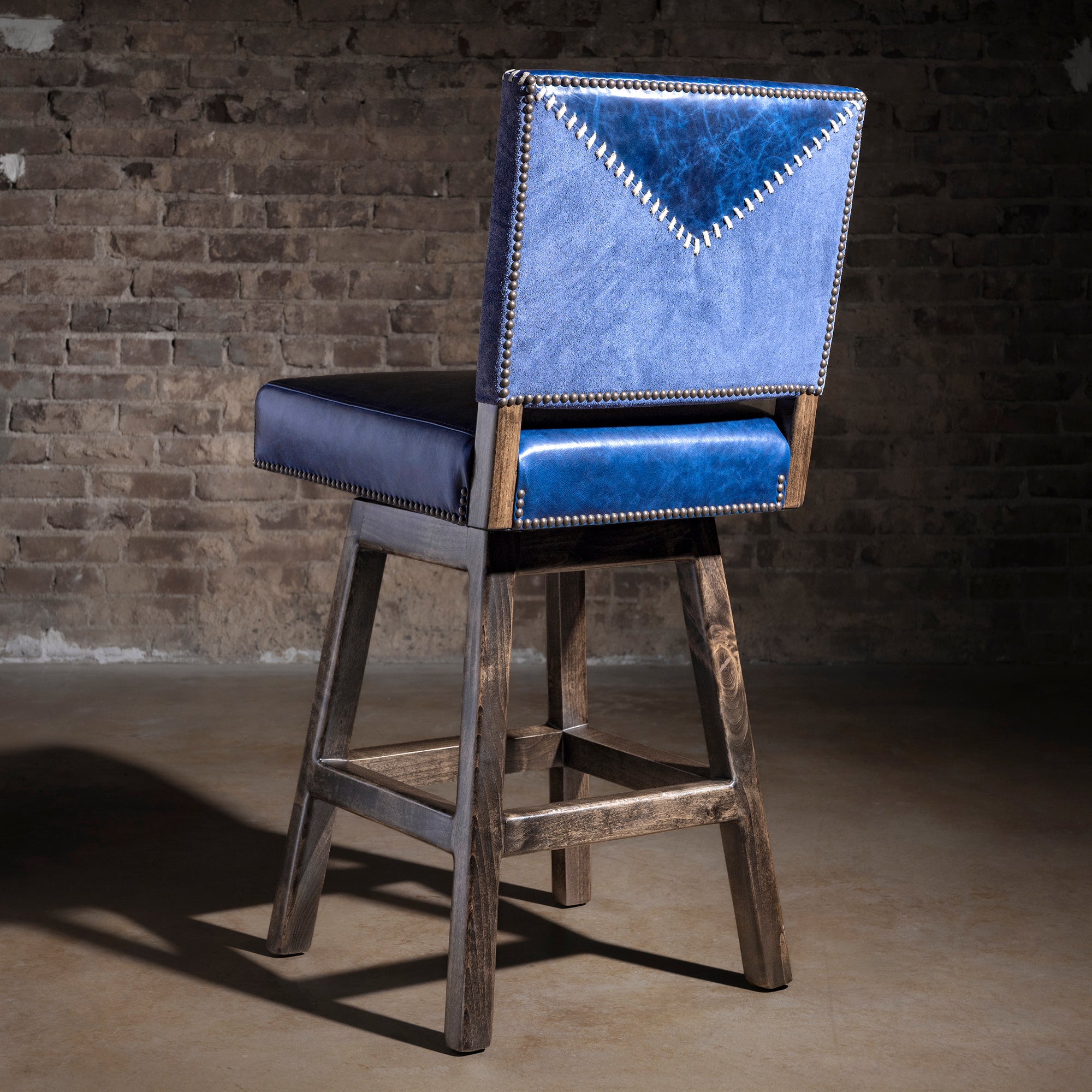 Back view of indigo yoke-stitched Western bar stool with suede panel, whipstitch detail, and nailhead border