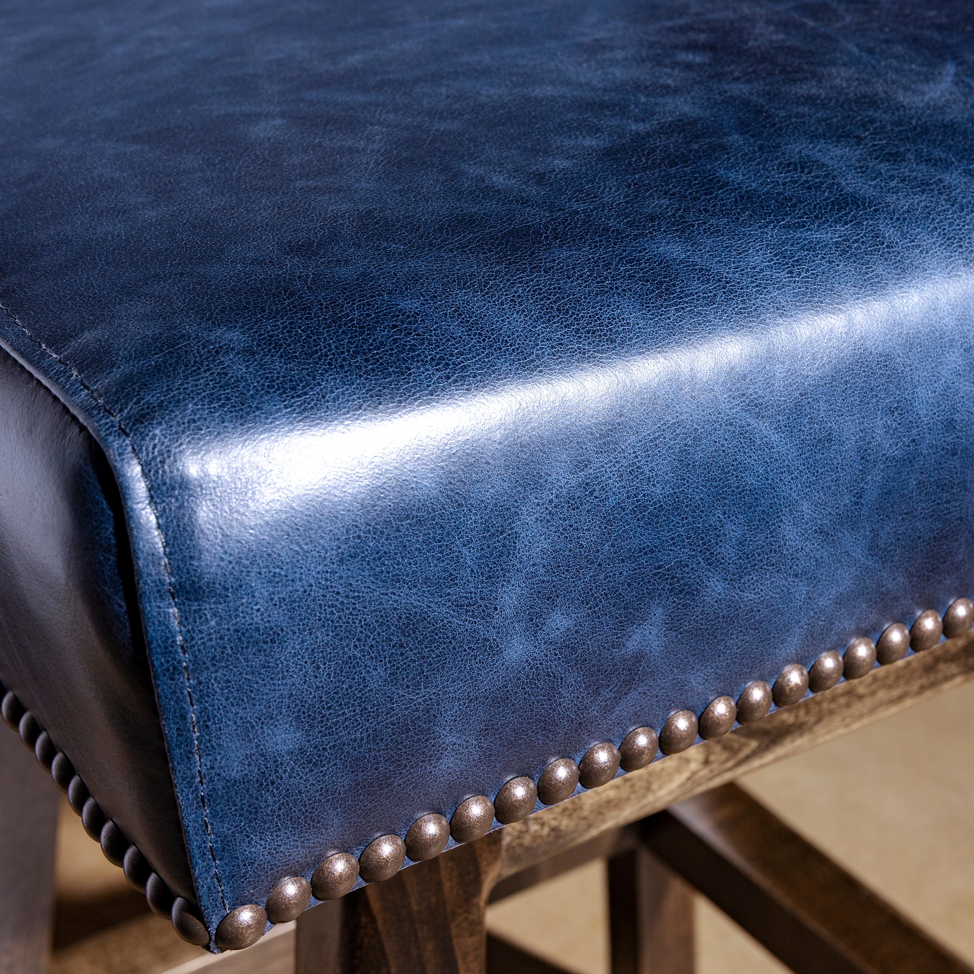 Closeup of indigo leather seat showing nailhead trim and premium leather grain on Western bar stool
