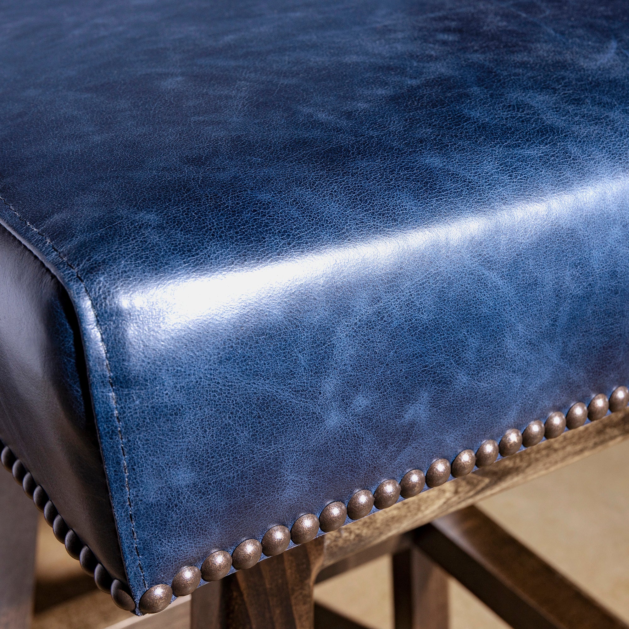 Closeup of indigo leather seat showing nailhead trim and premium leather grain on Western bar stool