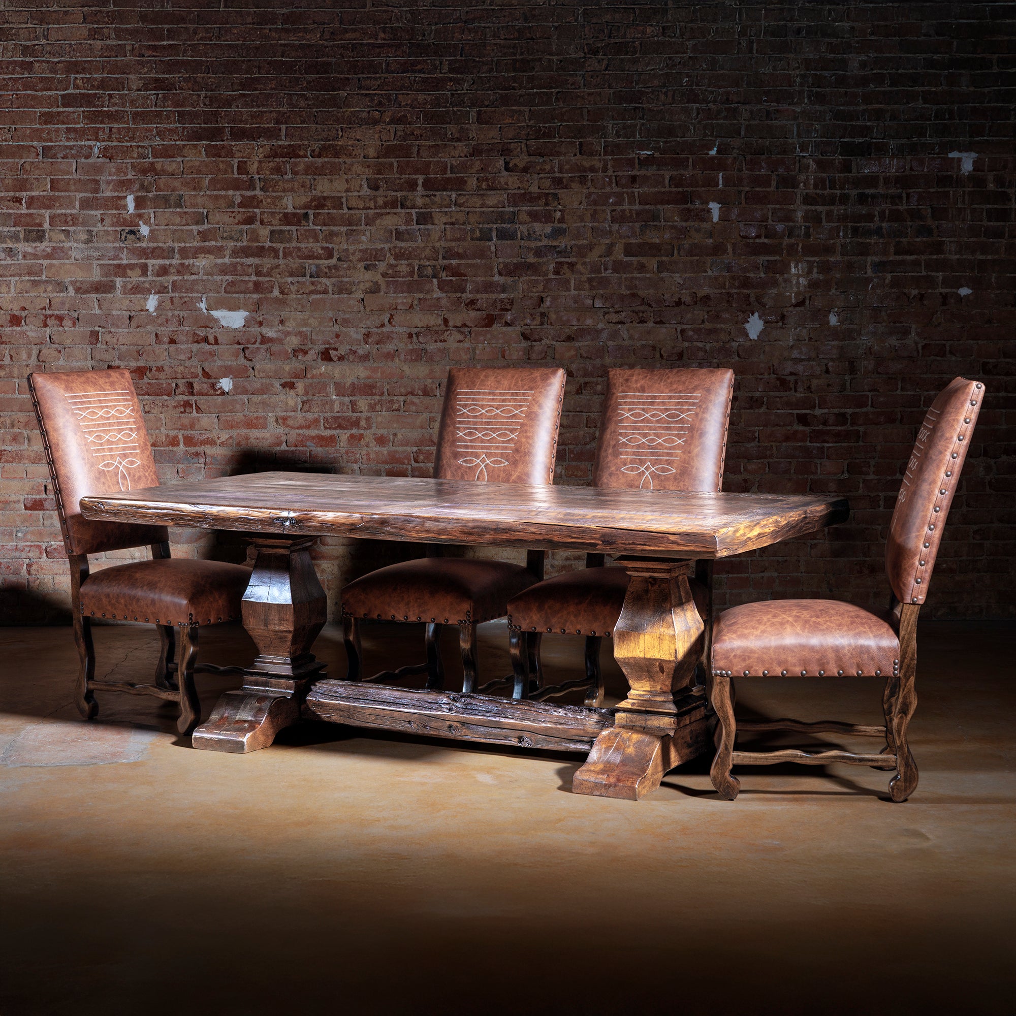 Western ranch dining table paired with leather chairs in rustic interior setting.