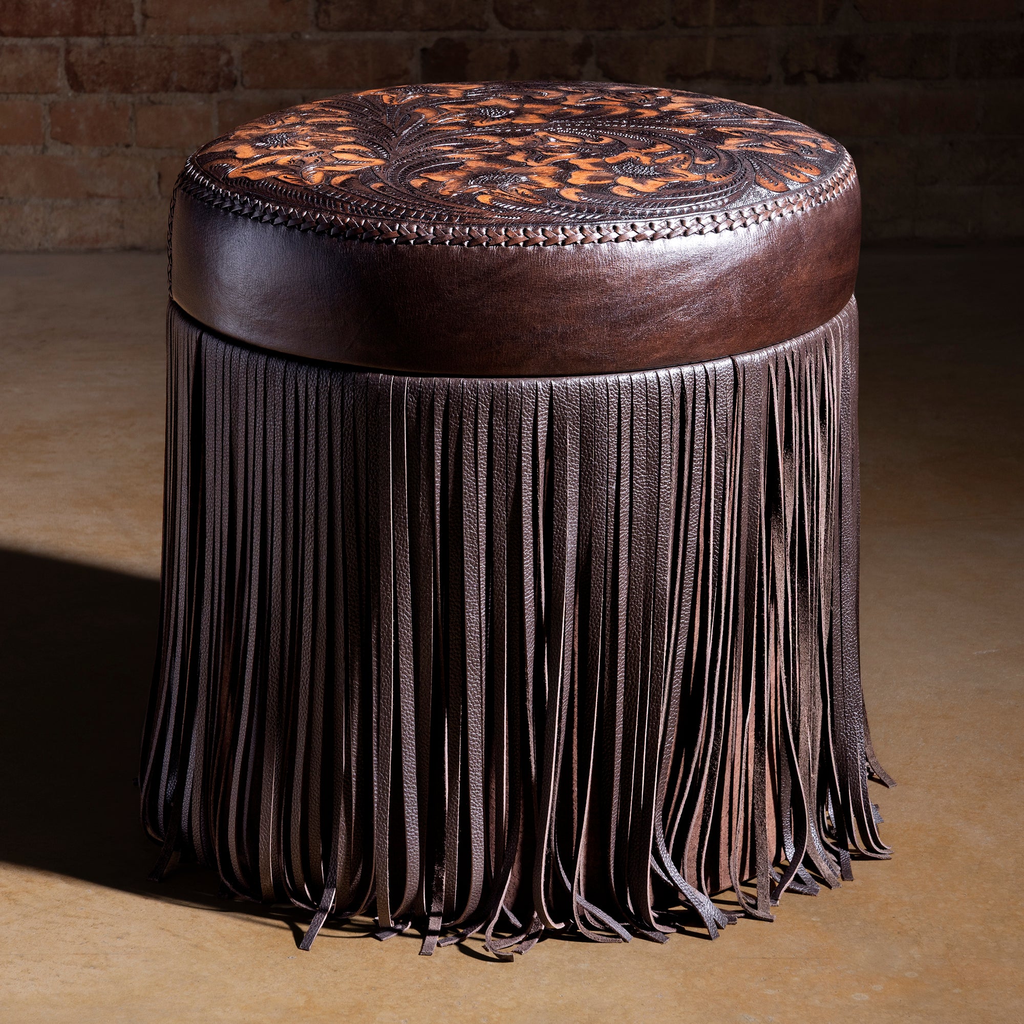 Hero shot of round tooled-leather fringe ottoman in luxury Western décor