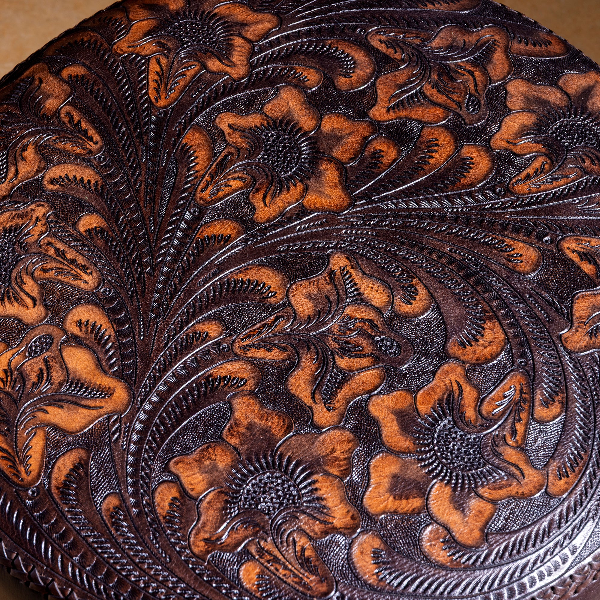 Side view of dark top-grain leather ottoman with long Western fringe trim