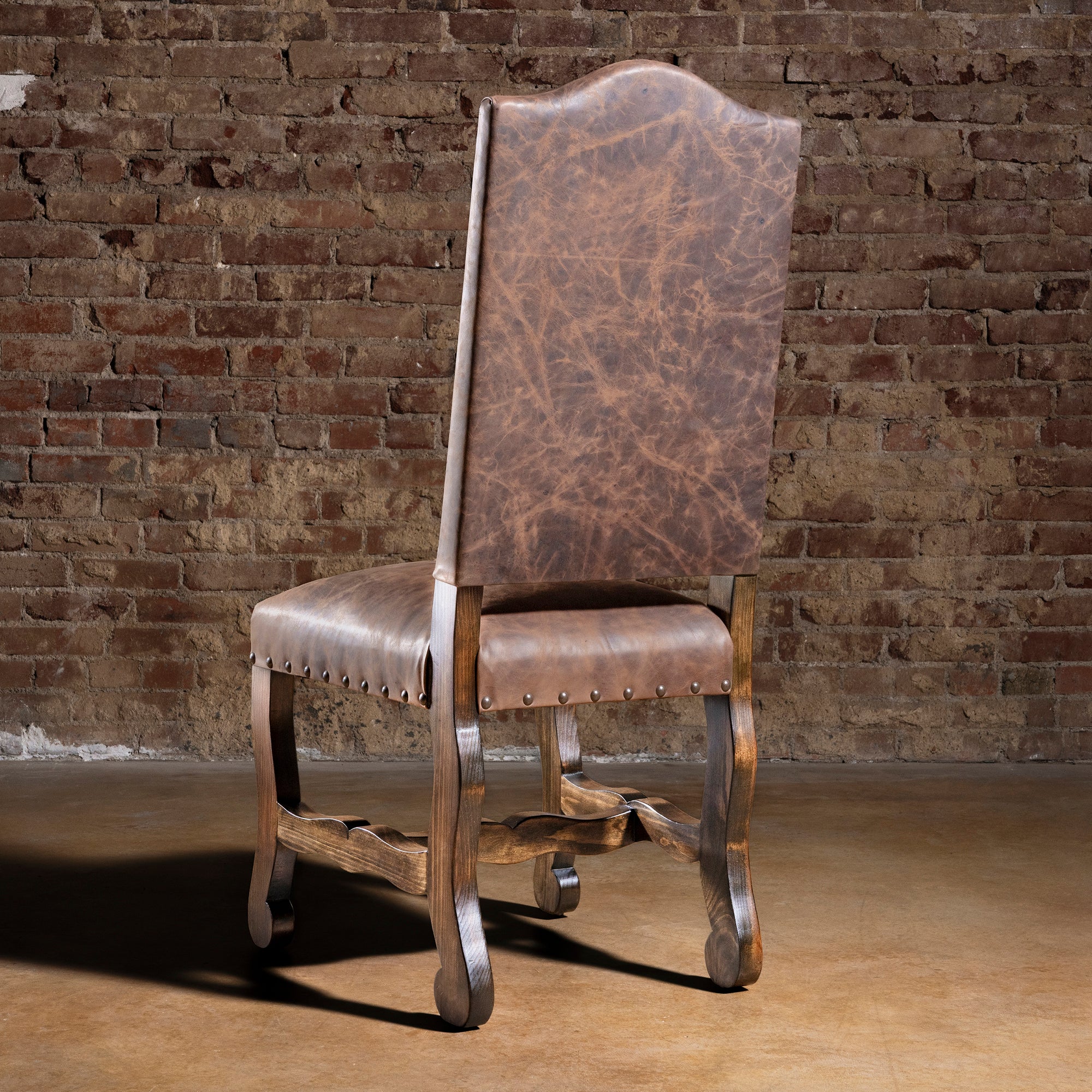 Back view of Pecos Canyon Western leather dining chair with tall arched back and wood legs