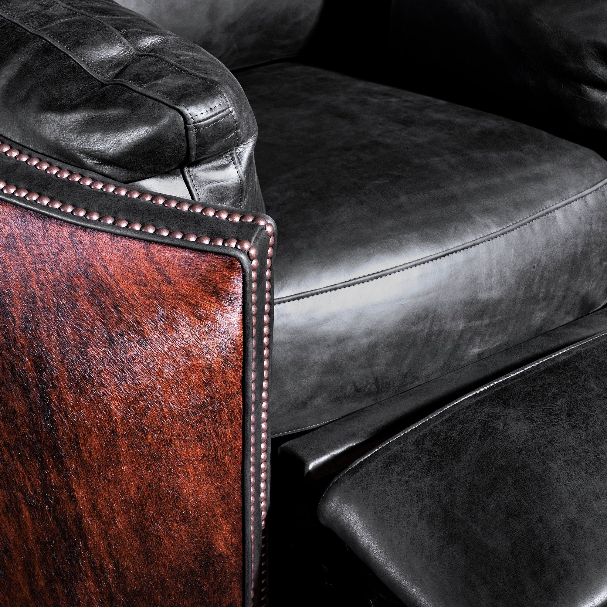 Close-up of nailhead trim, black leather seat, and brindle cowhide panel—Rio Lobo recliner