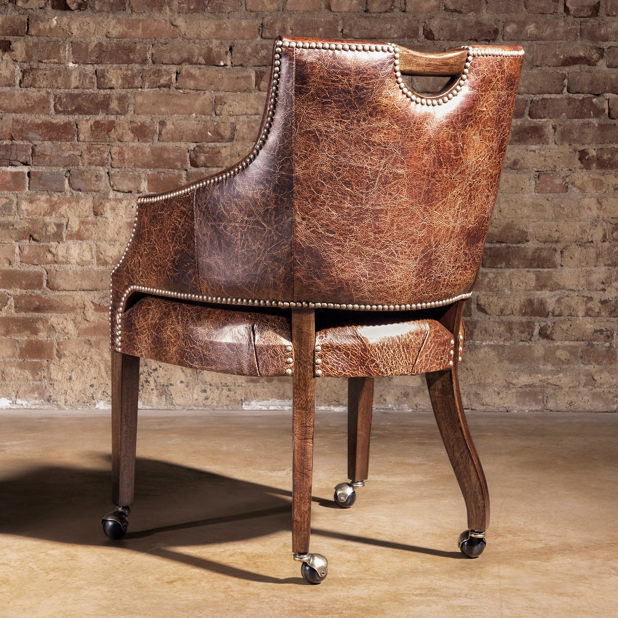 Back view of distressed leather game chair with nailhead trim and handle