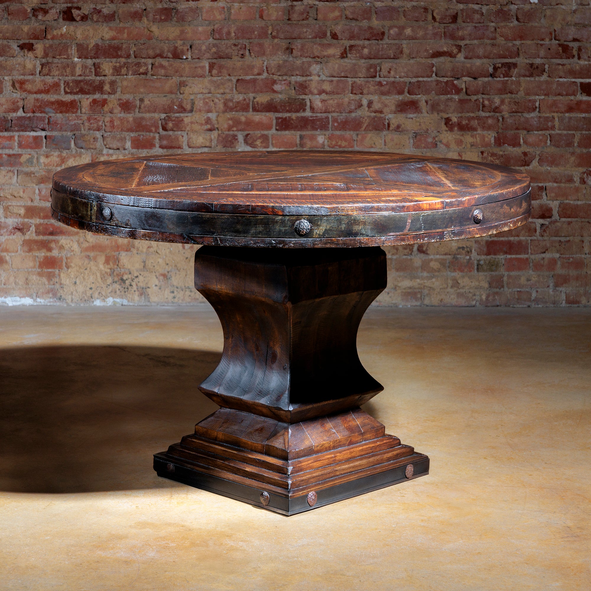 Reclaimed wood round dining table with rustic iron trim and pedestal base