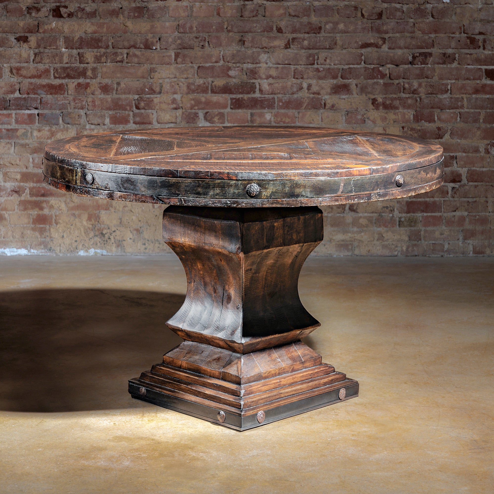 Reclaimed wood round dining table with rustic iron trim and pedestal base