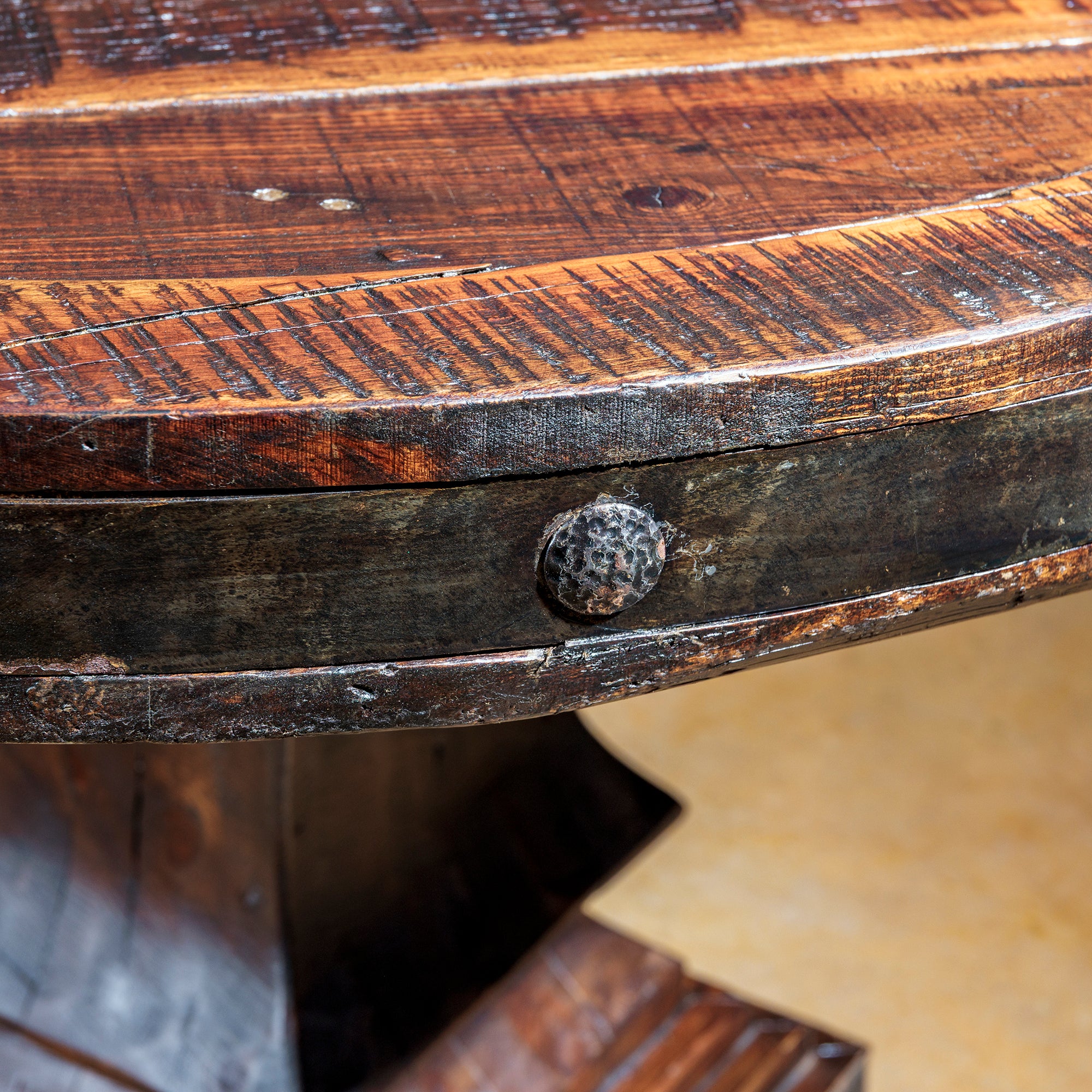 Close-up of hammered iron rivets and aged edge detailing on Western table