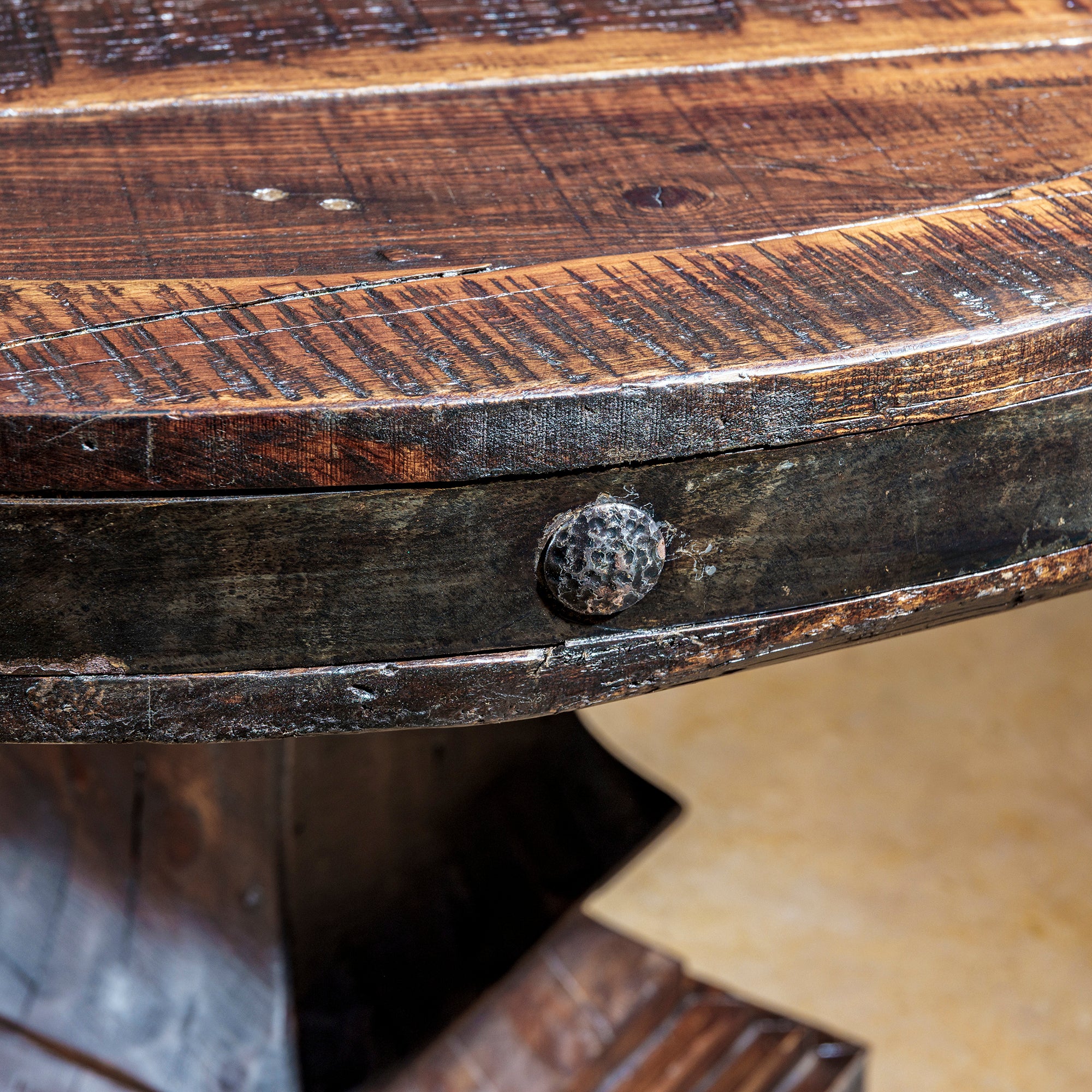 Close-up of hammered iron rivets and aged edge detailing on Western table