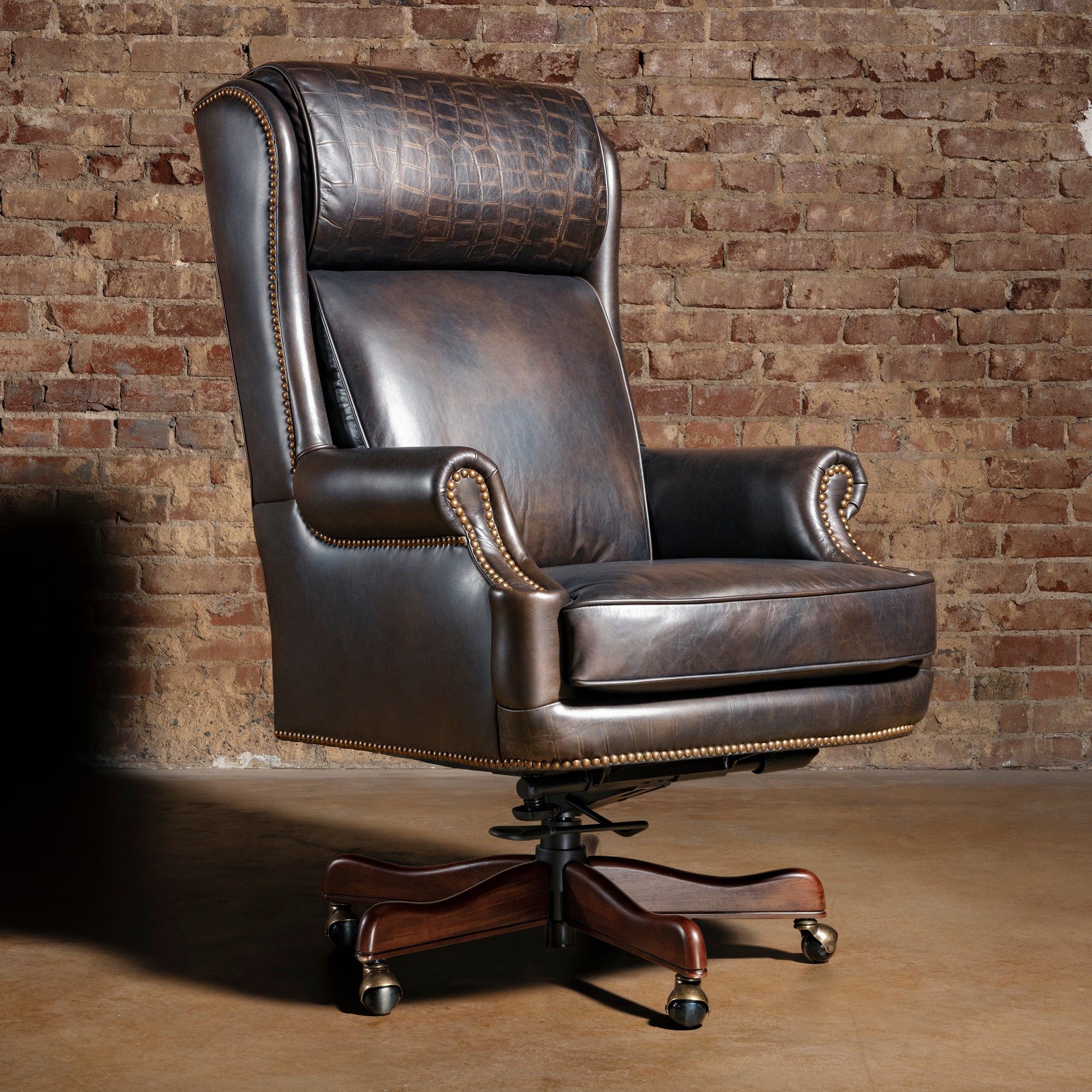 High back Western leather executive desk chair with croc-embossed headrest, antique nailheads, and wood caster base.