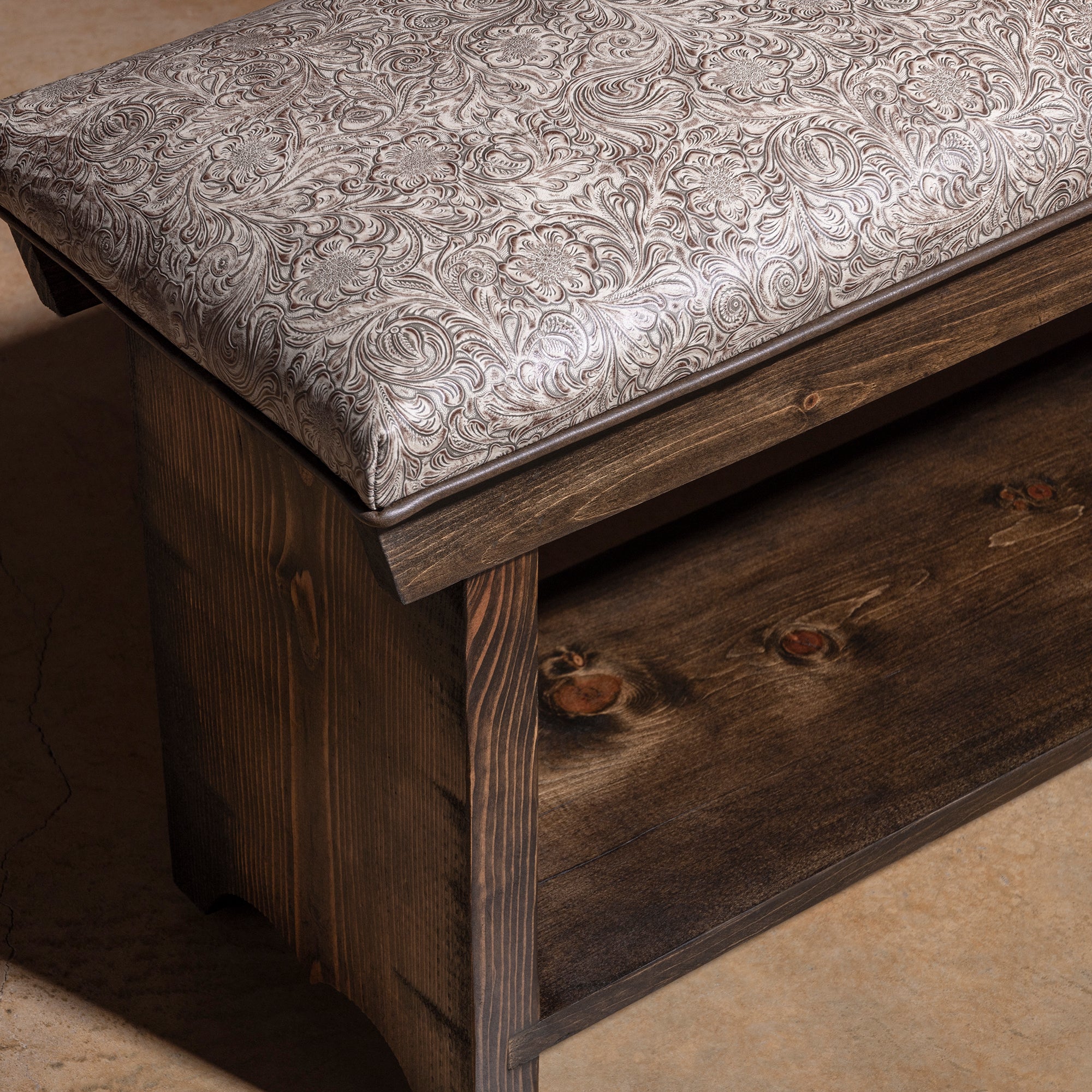 Saddle Bloom western bench corner detail with tooled leather cushion, dark stained wood frame, and handcrafted finish.