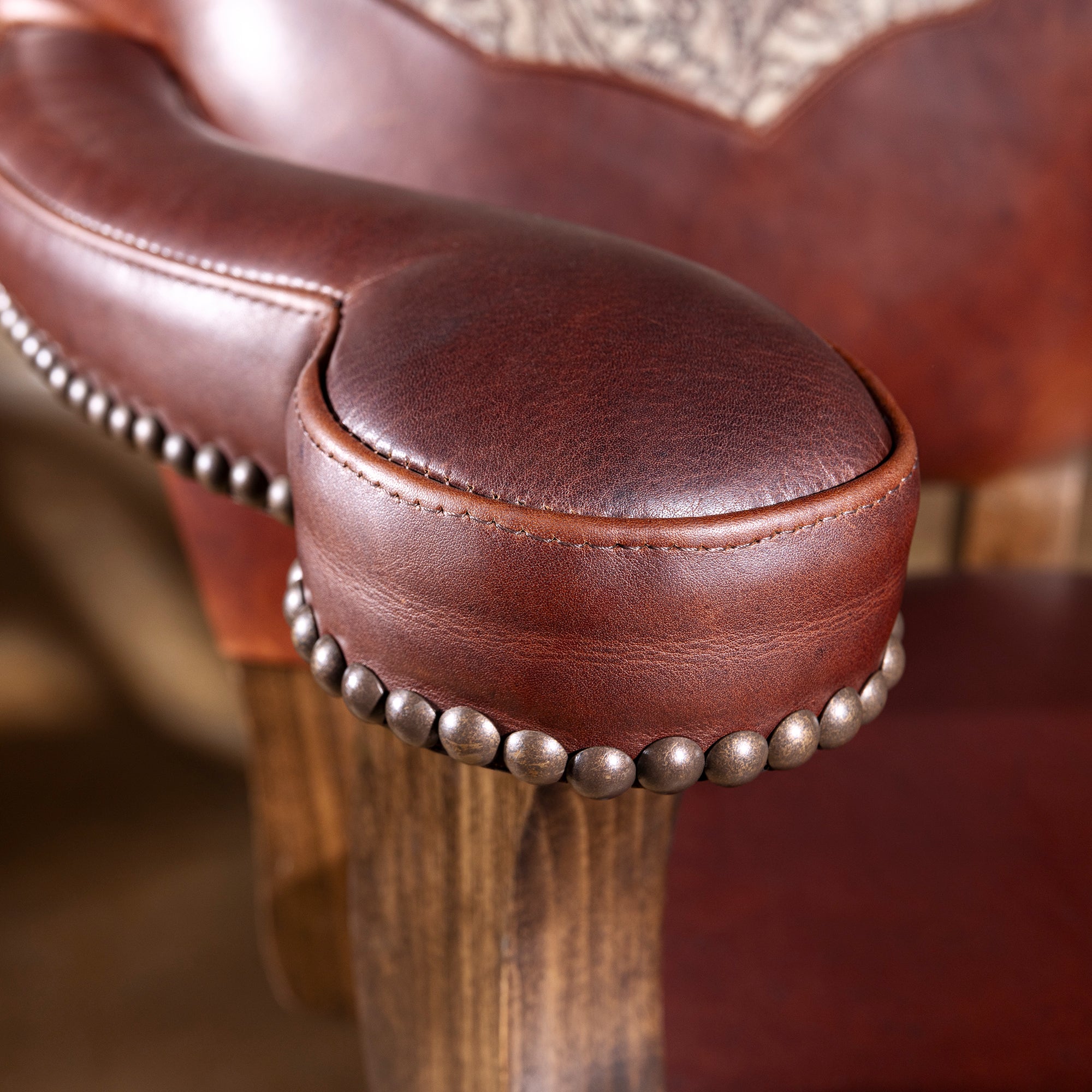Close-up of padded leather armrest on Saddlecrest Tooled Leather Western bar stool