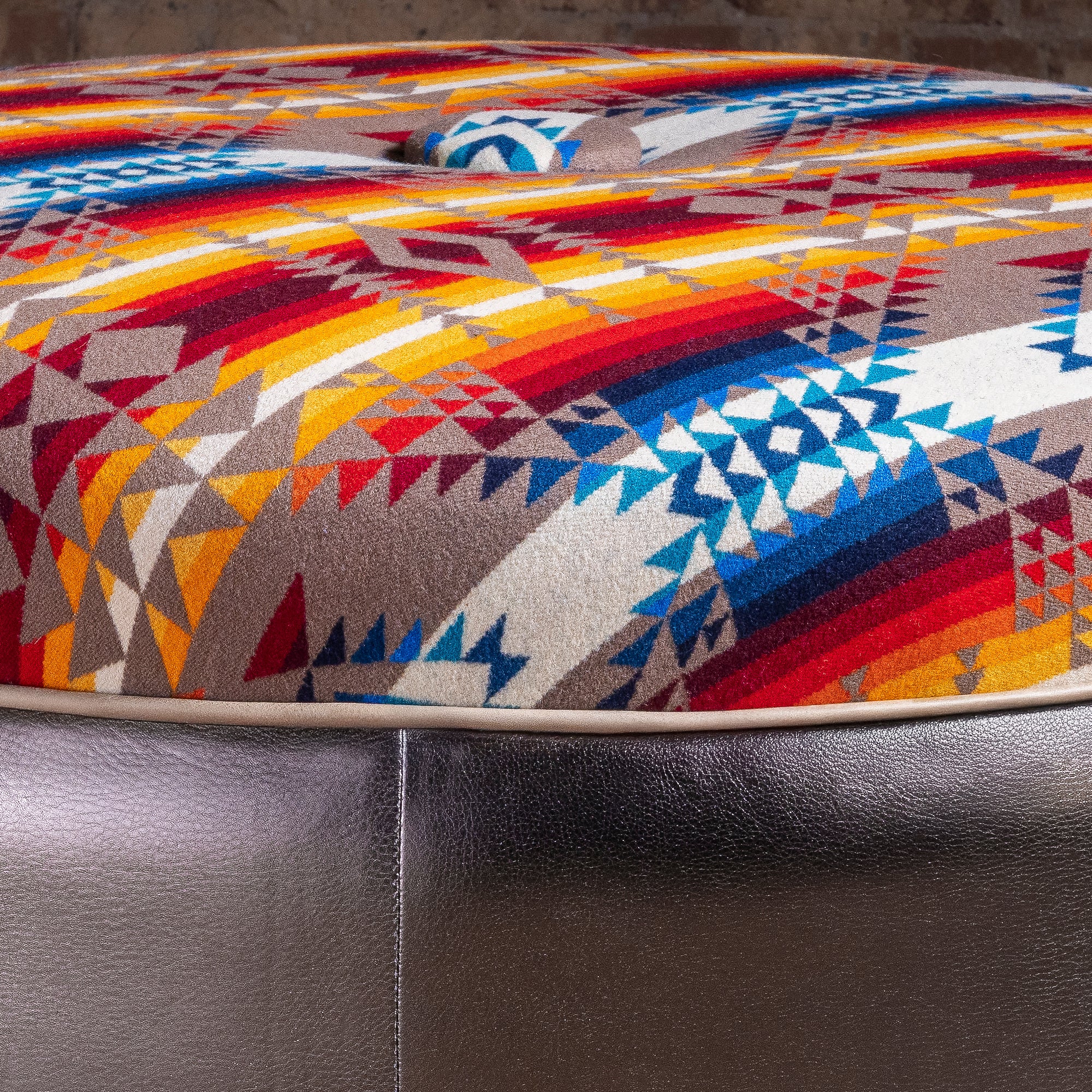 Close-up of Pendleton Southwest textile and dark leather base on round Western ottoman